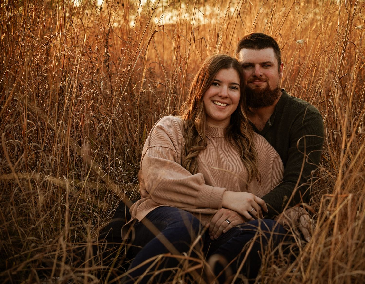 Wisconsin Couple and Engagement Photographer - Couple sitting in a field in fall during an engagement session in Wisconsin during sunset.