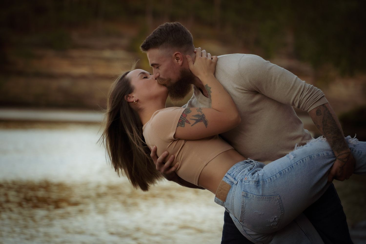 Wisconsin Couple and Engagement Photographer - Couple kissing on riverbank in fall during an engagement session in Wisconsin during sunset.