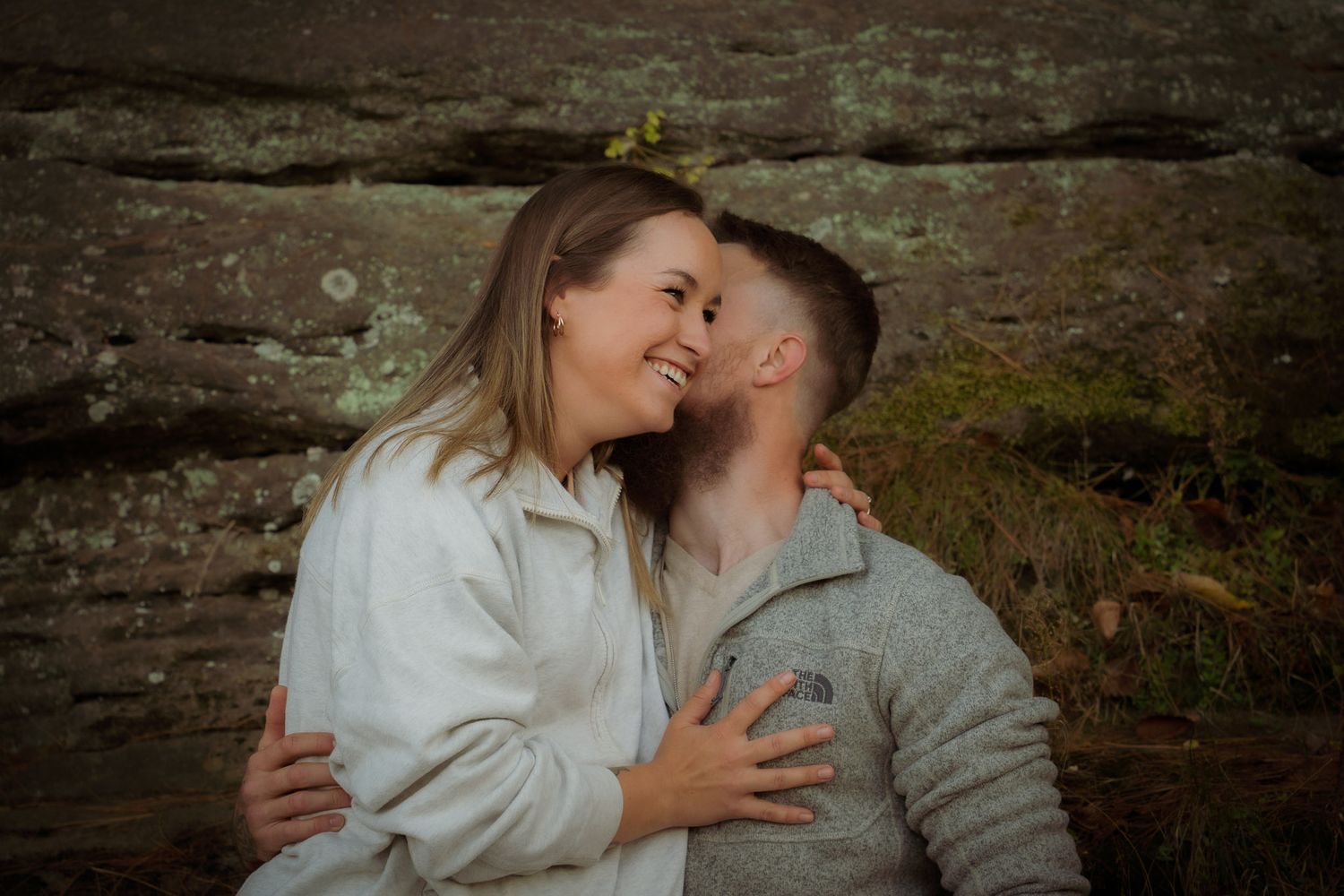 Wisconsin Couple and Engagement Photographer - Couple smiling in fall during an engagement session in Wisconsin during sunset by cliff/rocks