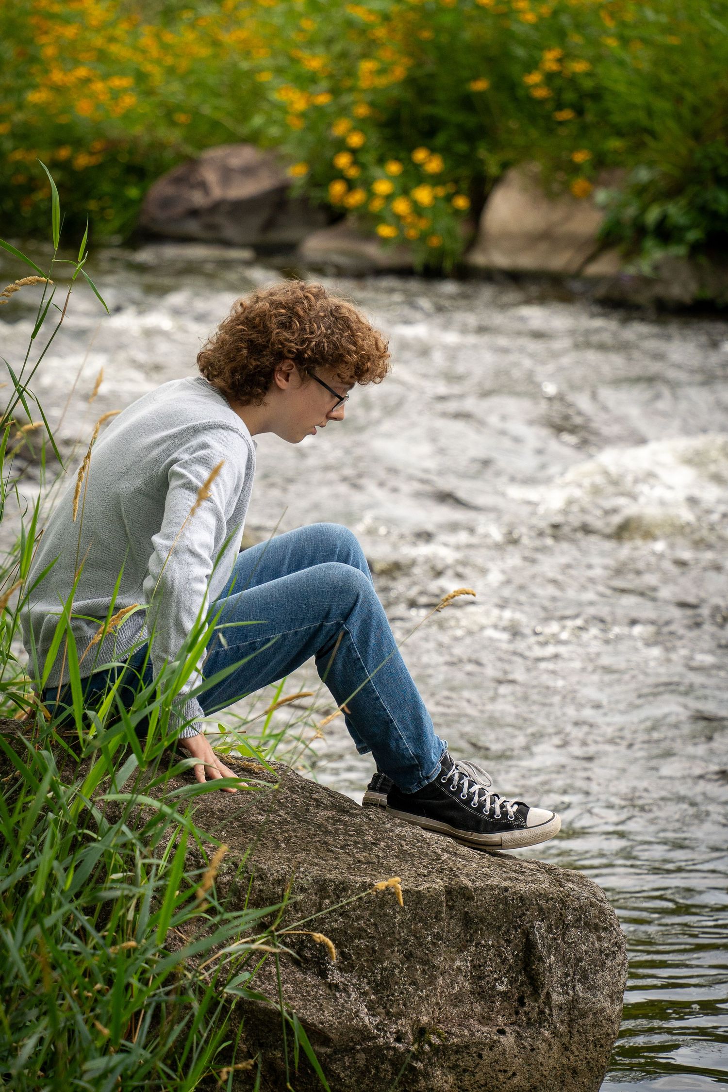 Wisconsin Senior and Portrait Photographer - Boy sitting on a rock on river smiling in Wisconsin during a summer senior portrait session.