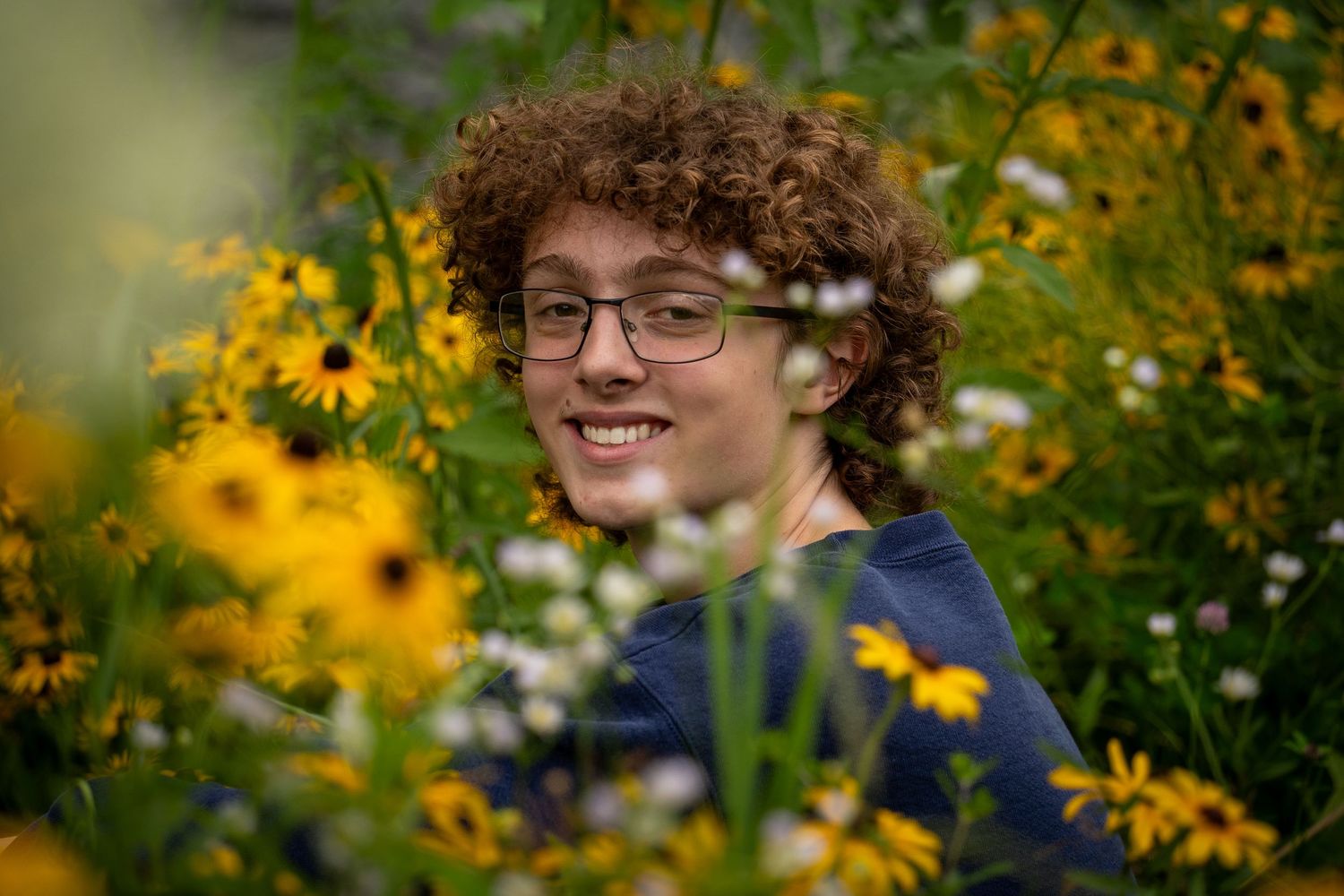 Wisconsin Senior and Portrait Photographer - Boy smiling with yellow flowers in Wisconsin during a summer senior portrait session.