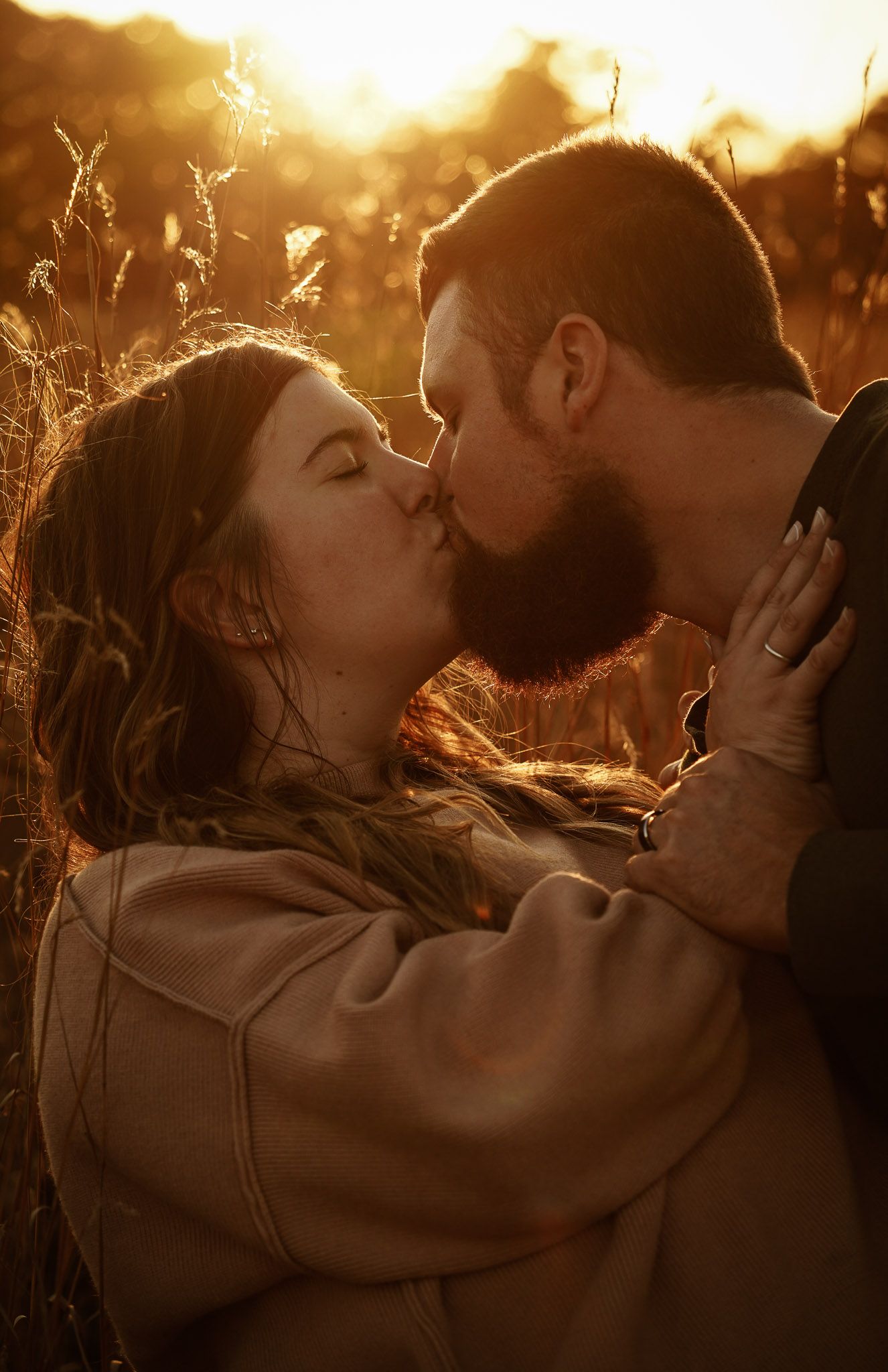 Wisconsin Couple and Engagement Photographer - Couple kissing in fall during sunset during engagement session in a field.