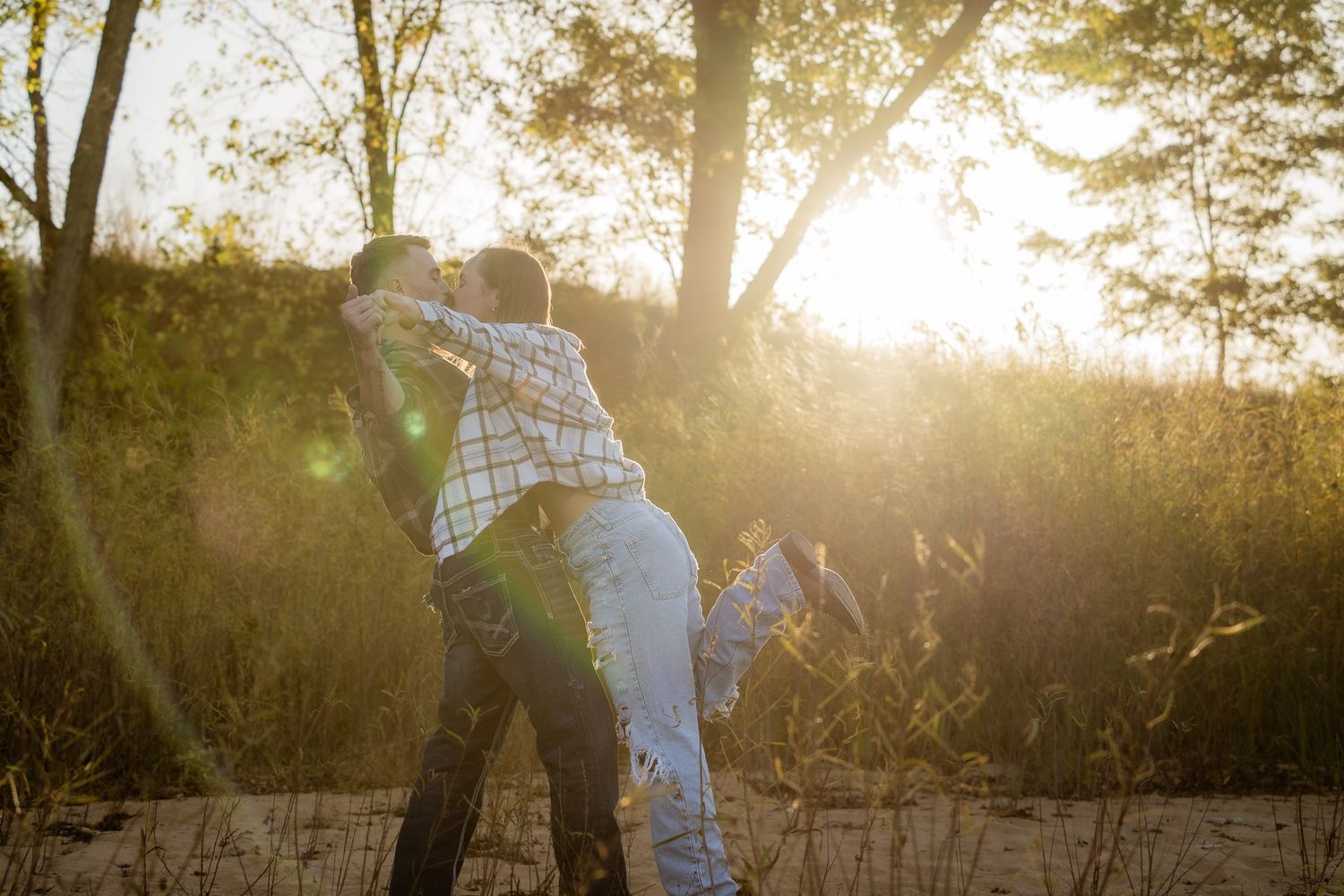 Wisconsin Couple and Engagement Photographer - Couple kissing on a beach in fall during an engagement session in Wisconsin during sunset.