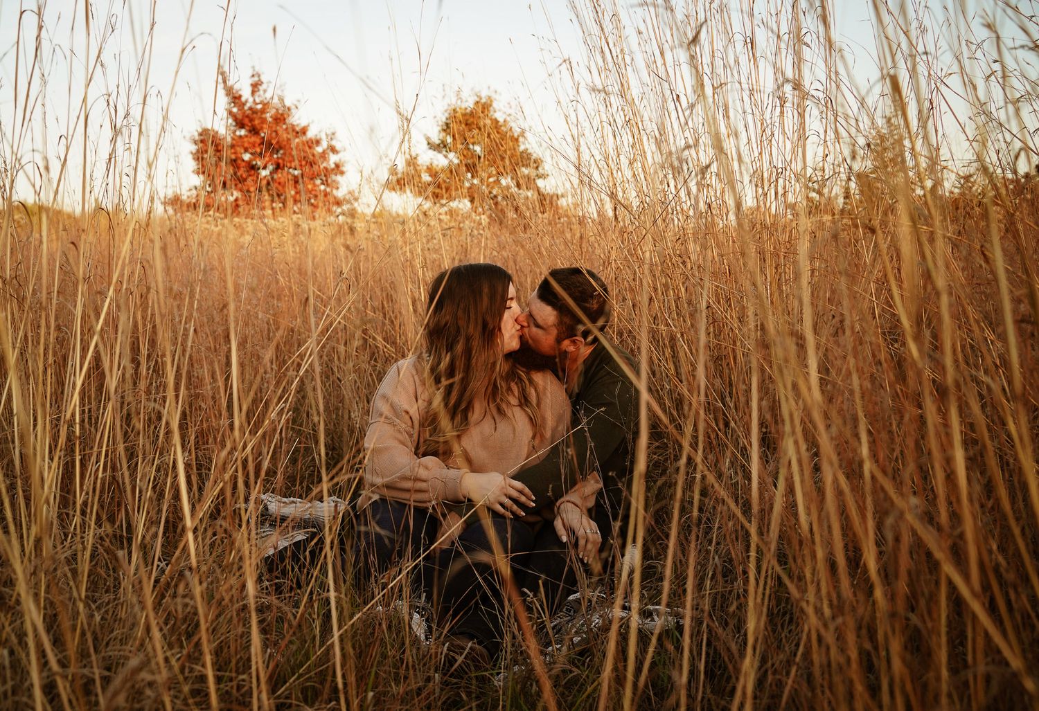 Wisconsin Couple and Engagement Photographer - Couple kissing in a field in fall during an engagement session during sunset in Wisconsin.