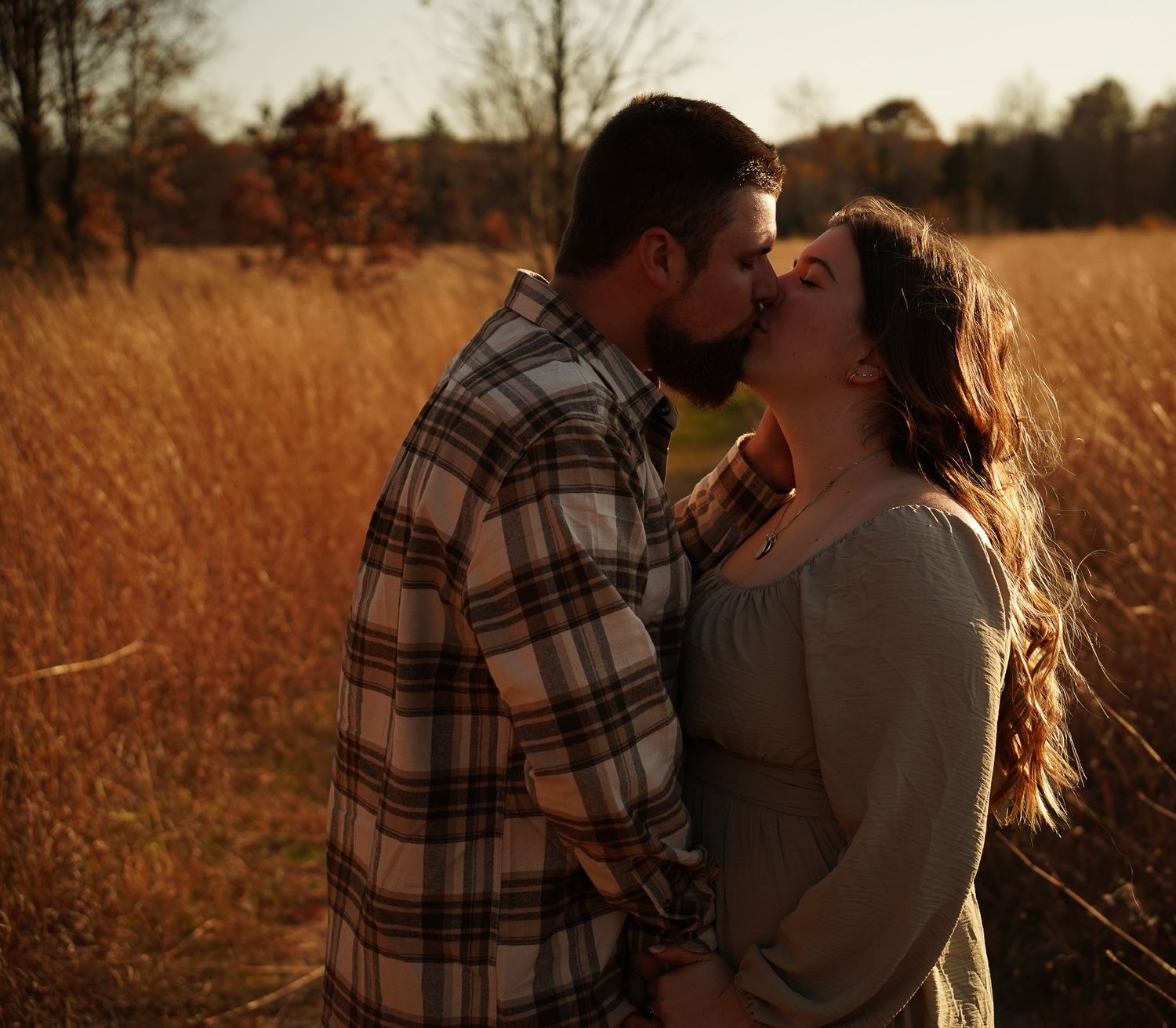 Wisconsin Couple and Engagement Photographer - Couple kissing in a field in fall during an engagement session in Wisconsin during sunset.