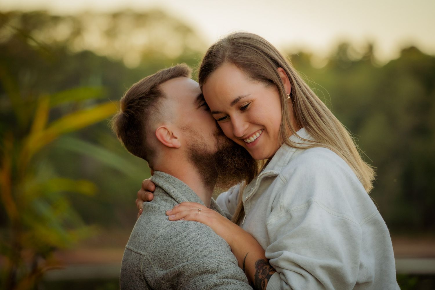 Wisconsin Couple and Engagement Photographer - Couple smiling on riverbank in fall during an engagement session in Wisconsin during sunset.