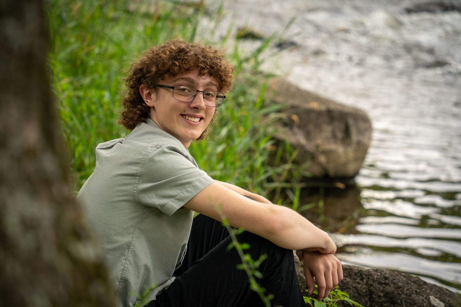 Wisconsin Senior and Portrait Photographer - Boy sitting on a rock on river smiling in Wisconsin during a summer senior portrait session.