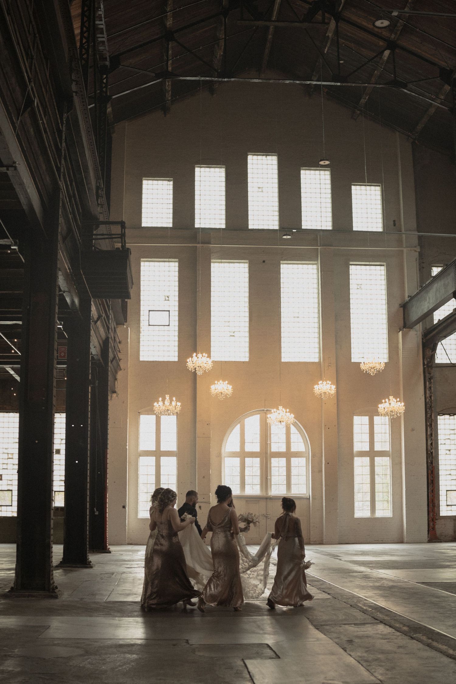 Bridesmaids in sunlit venue interior with tall windows, chandeliers, and industrial-style beams  Northern Pacific Center Brainerd Minnesota