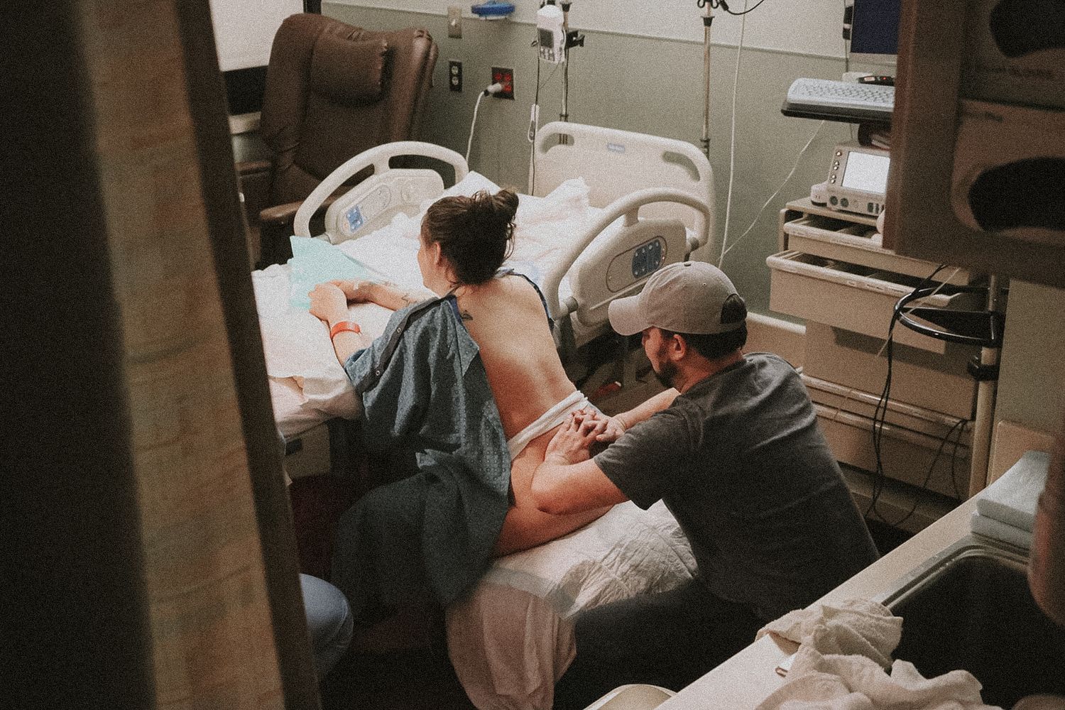 Intimate moment husband helping wife with contractions, rubbing her back in hospital birthing center