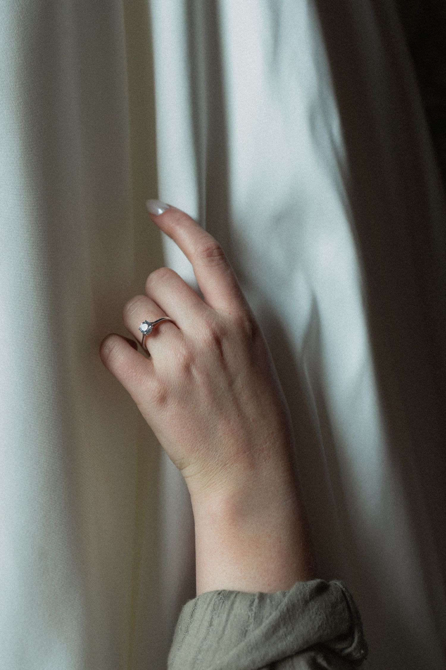 Close-up of hands pulling back white wedding dress in soft natural light at the Ivy House in Milwaukee Wisconsin
