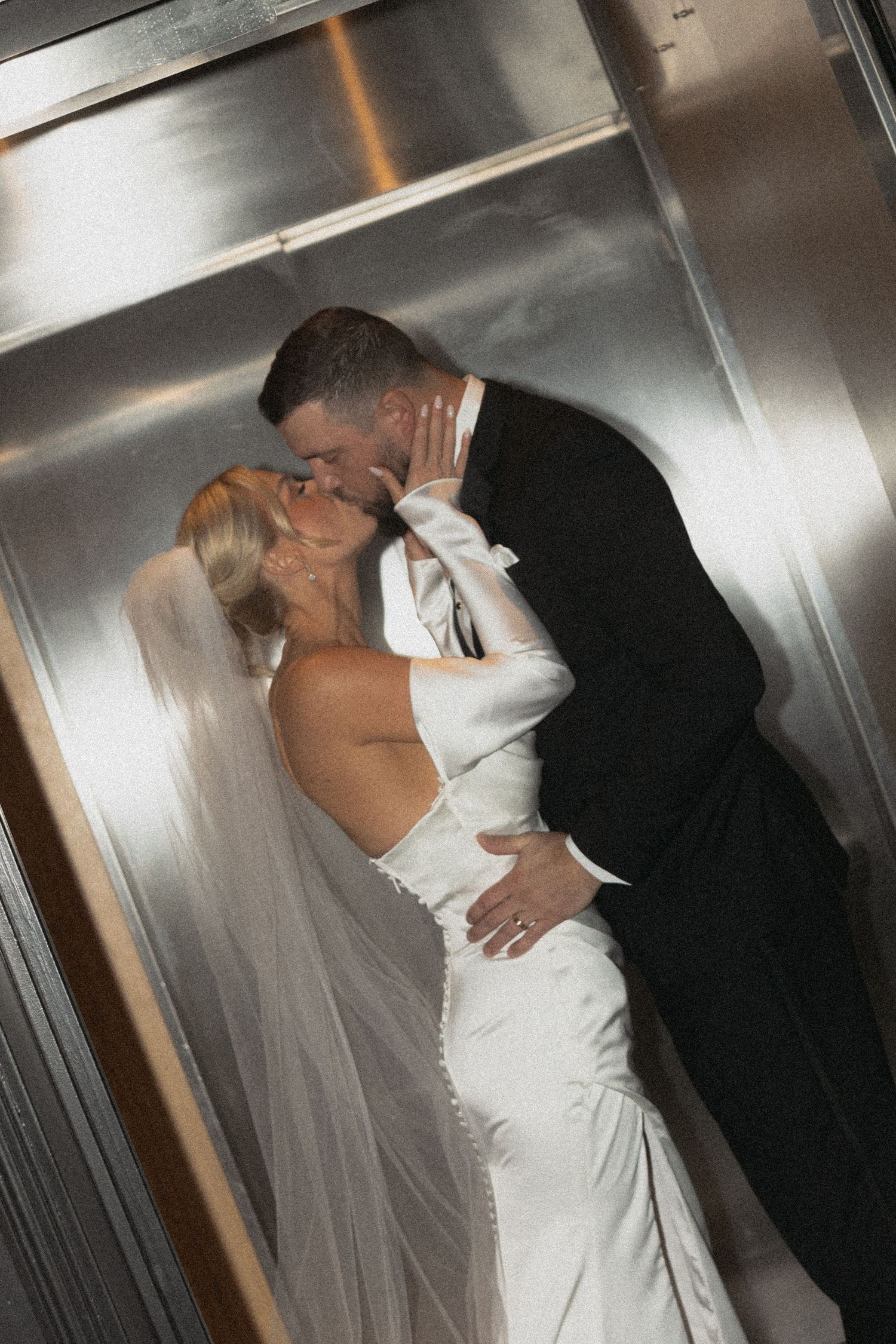 A direct flash shot of a couple sharing an intimate moment in a modern elevator on their wedding day at Le Venere in Saint Paul Minnesota