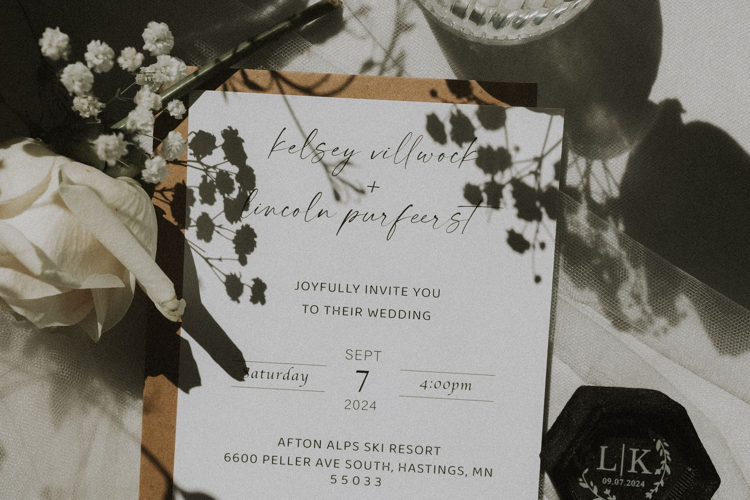 A minimalist wedding invitation with floral details in black and white natural sun shadows and direct light