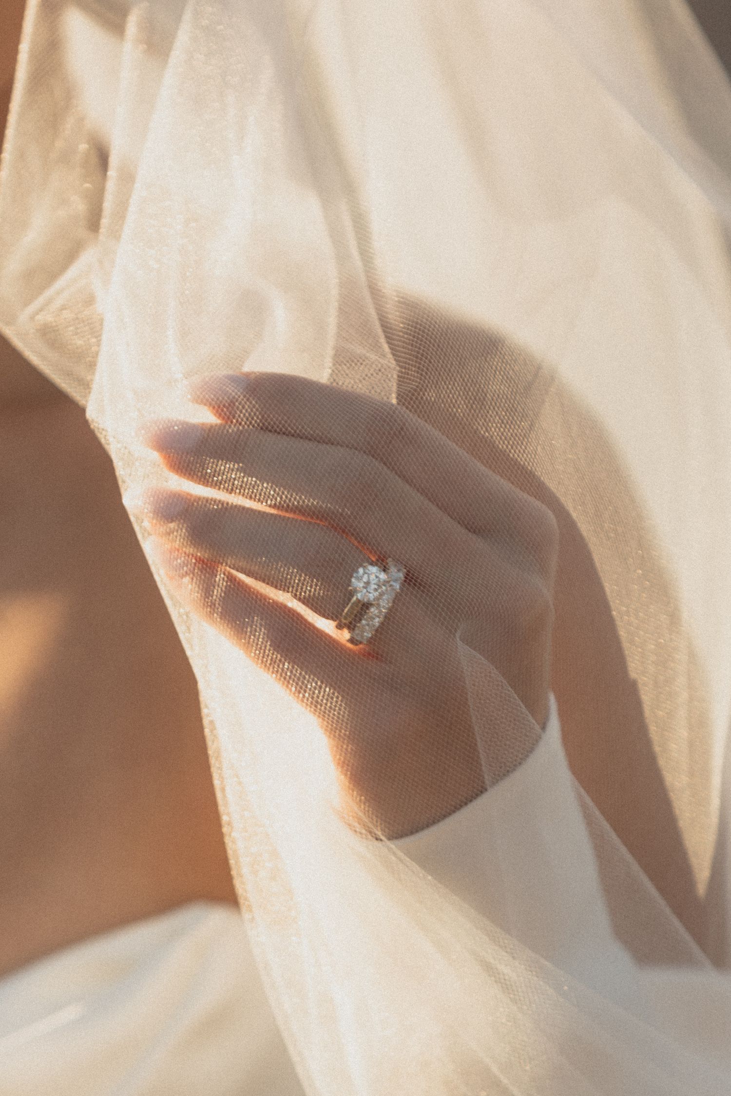 An elegant diamond ring displayed against soft white tulle in golden lightat Le Venere in Saint Paul Minnesota
