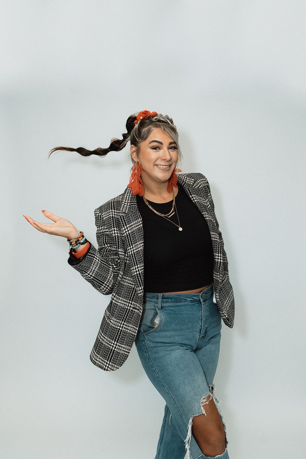 A person in a plaid blazer and jeans strikes dynamic poses against a light background.