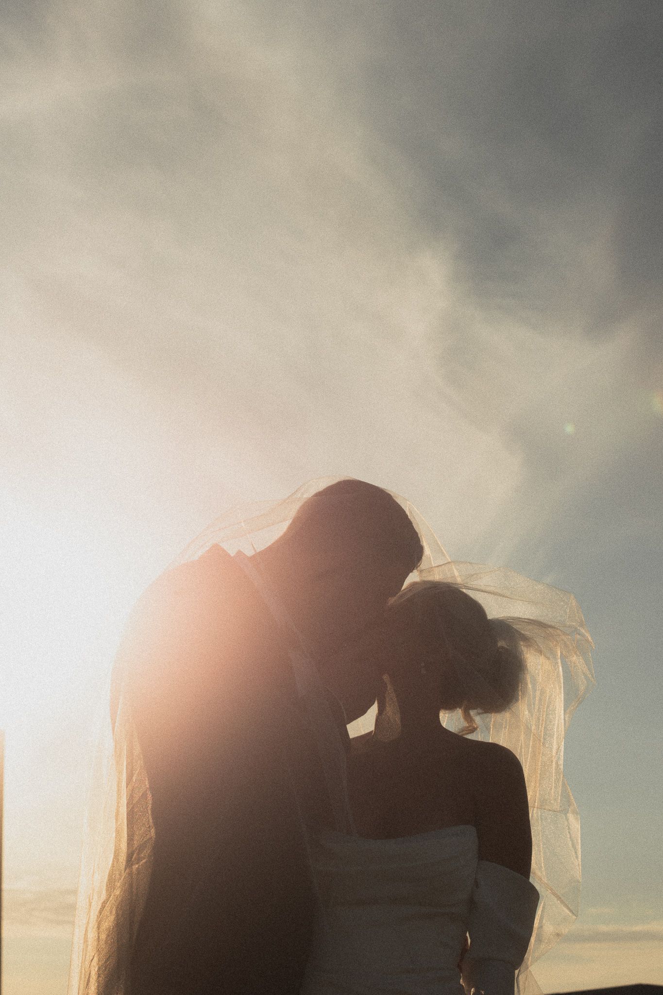 Silhouetted couple embraces against a dreamy sunset sky with soft clouds roof top of Le Venere in Saint Paul Minnesota
