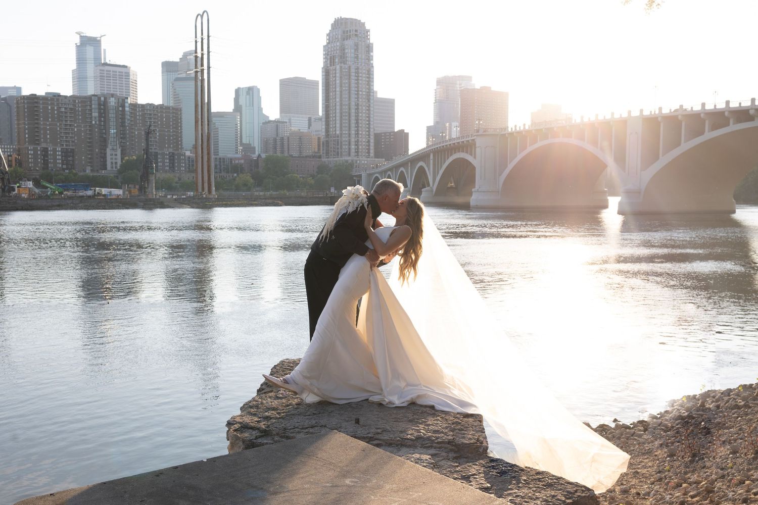 Newlyweds share an intimate moment by the Minneapolis river at golden hour Stone Arch Bridge Saint Anthony Main