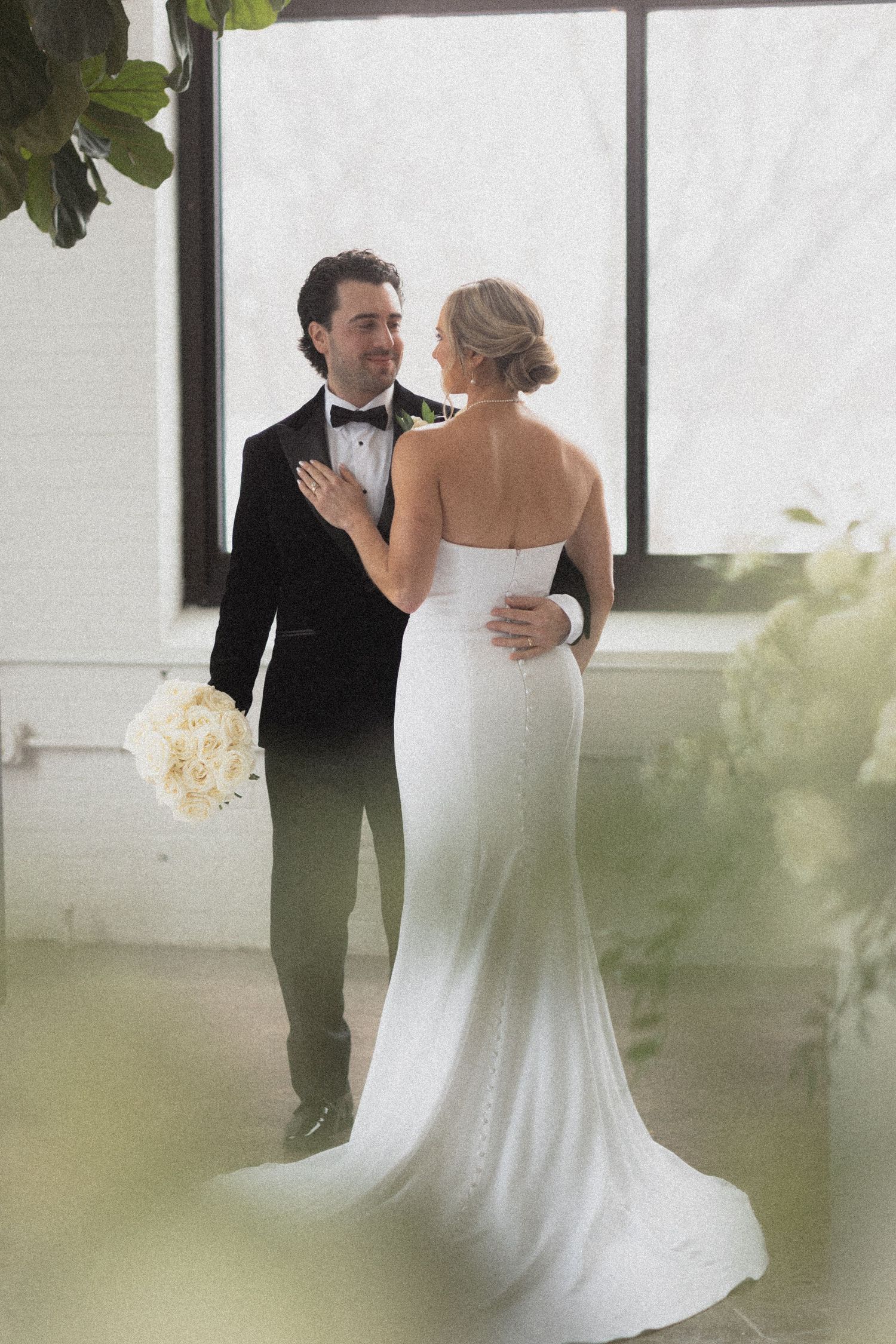 Elegant couple in wedding attire sharing an intimate moment by large windows with natural light at Urban Daisy Events Minneapolis Minnesota