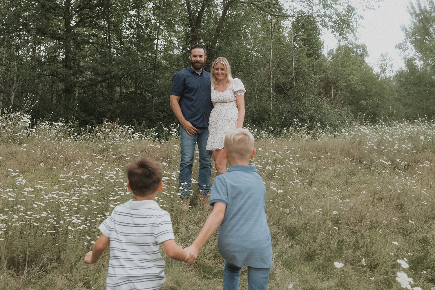Family walking together through a meadow of white wildflowers on a summer day.