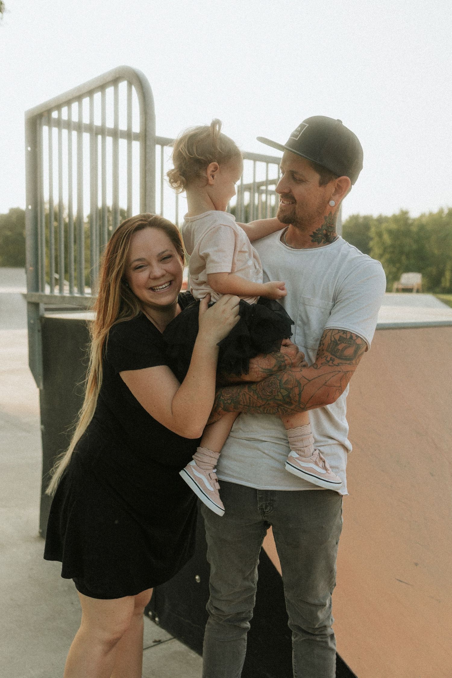 Alternative style family sharing tender moments together on outdoor skatepark during sunset.