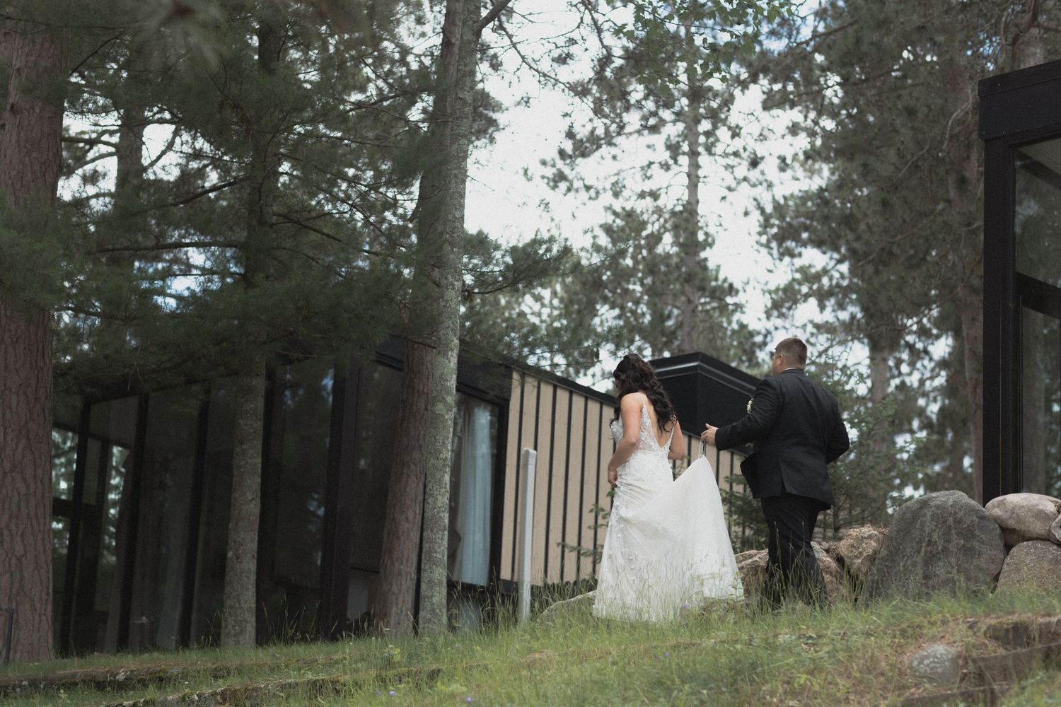 A scenic outdoor wedding ceremony setup with wooden chairs arranged in rows among tall pine trees at Catalyst by Nature Link Nisswa MN