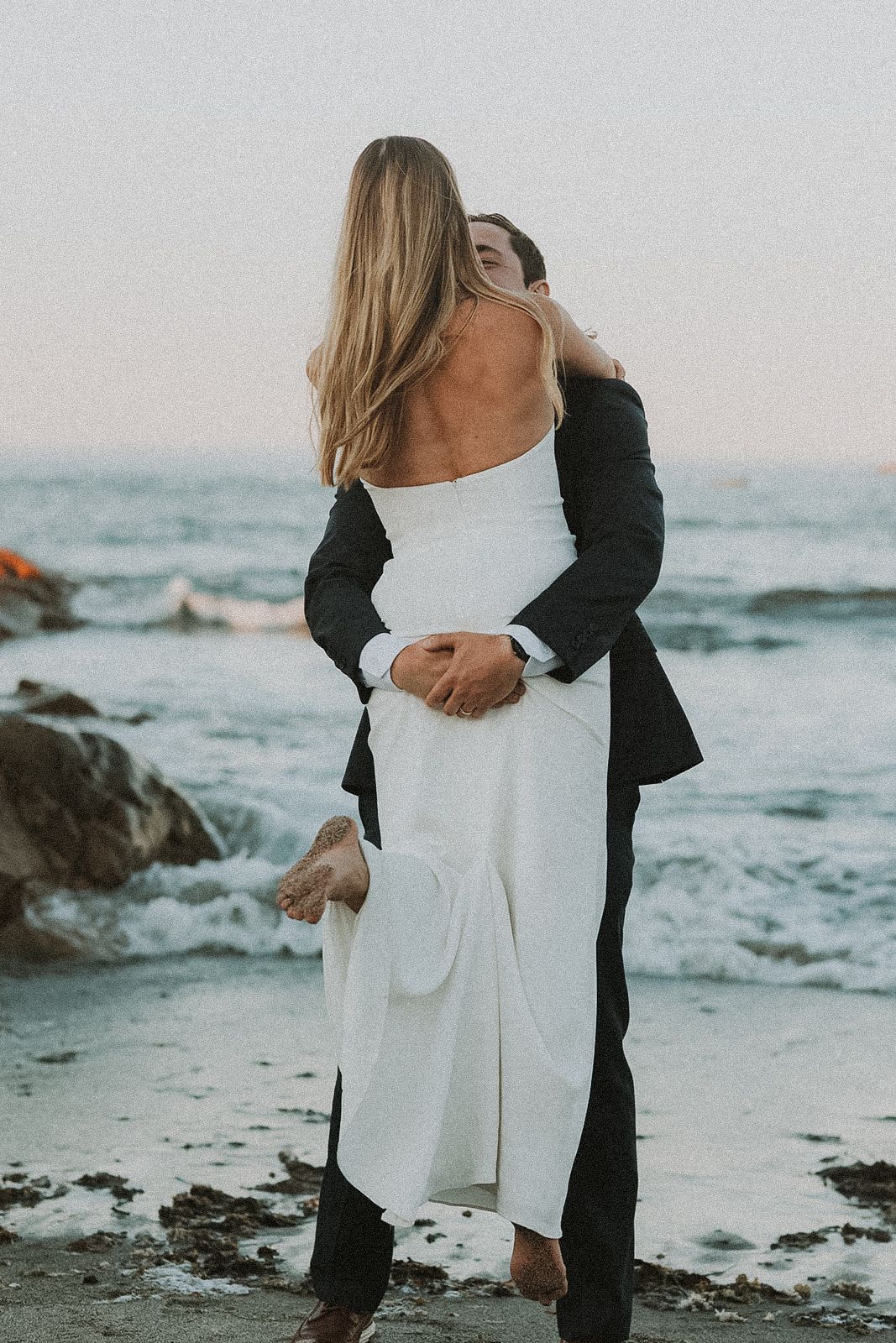 Romantic Massachusetts coastal wedding photos with couple embracing against ocean backdrop at sunset