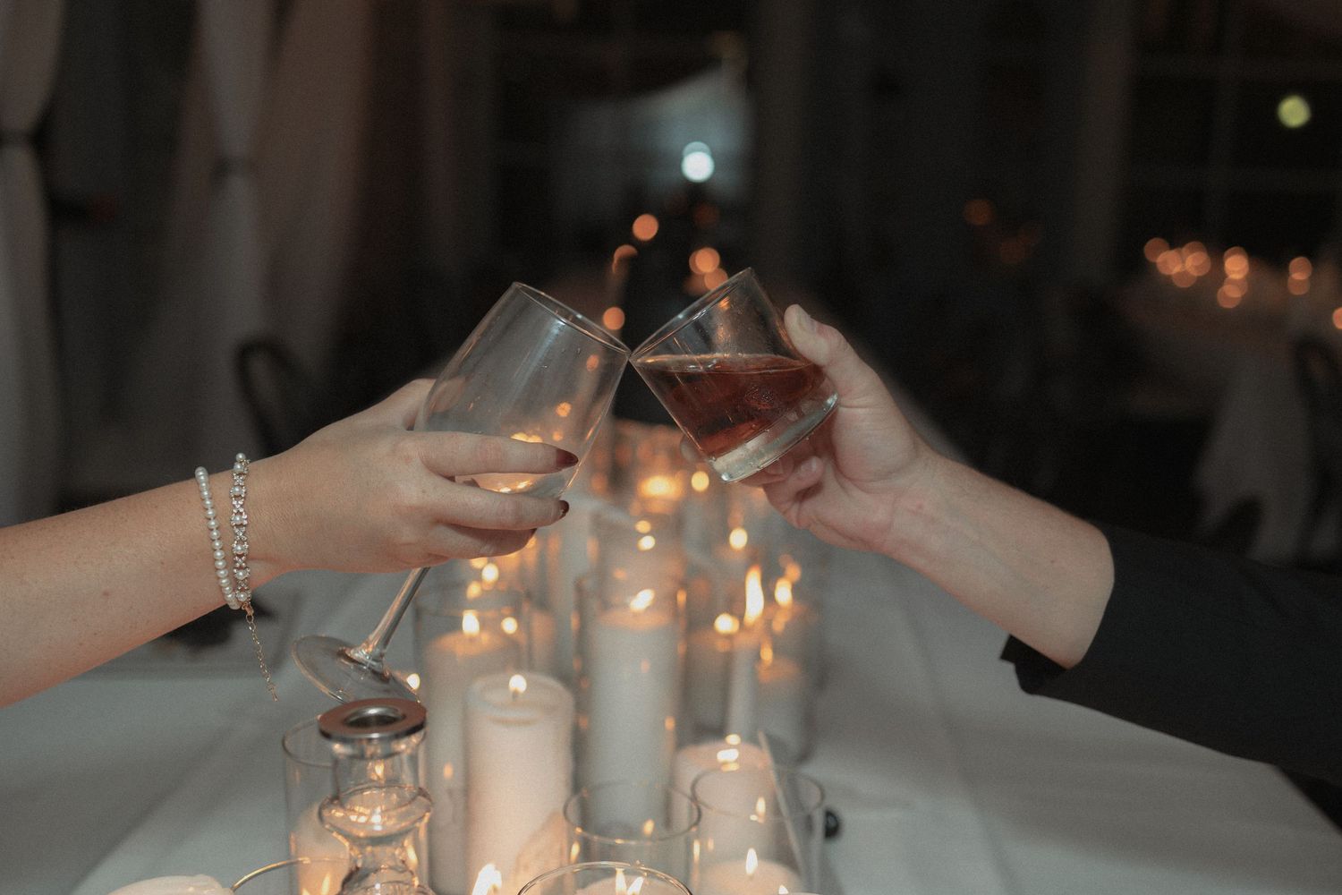 A candlelit table setting at a wedding reception with white linens and elegant glassware creates a romantic atmosphere.