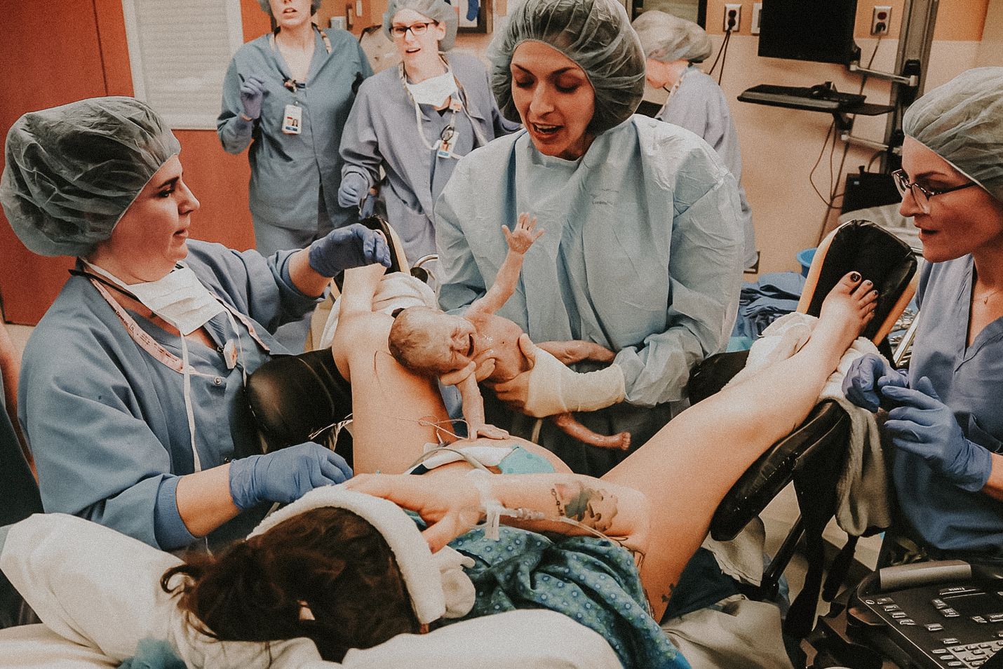 Medical staff attending to a patient in a hospital delivery room setting, baby being born