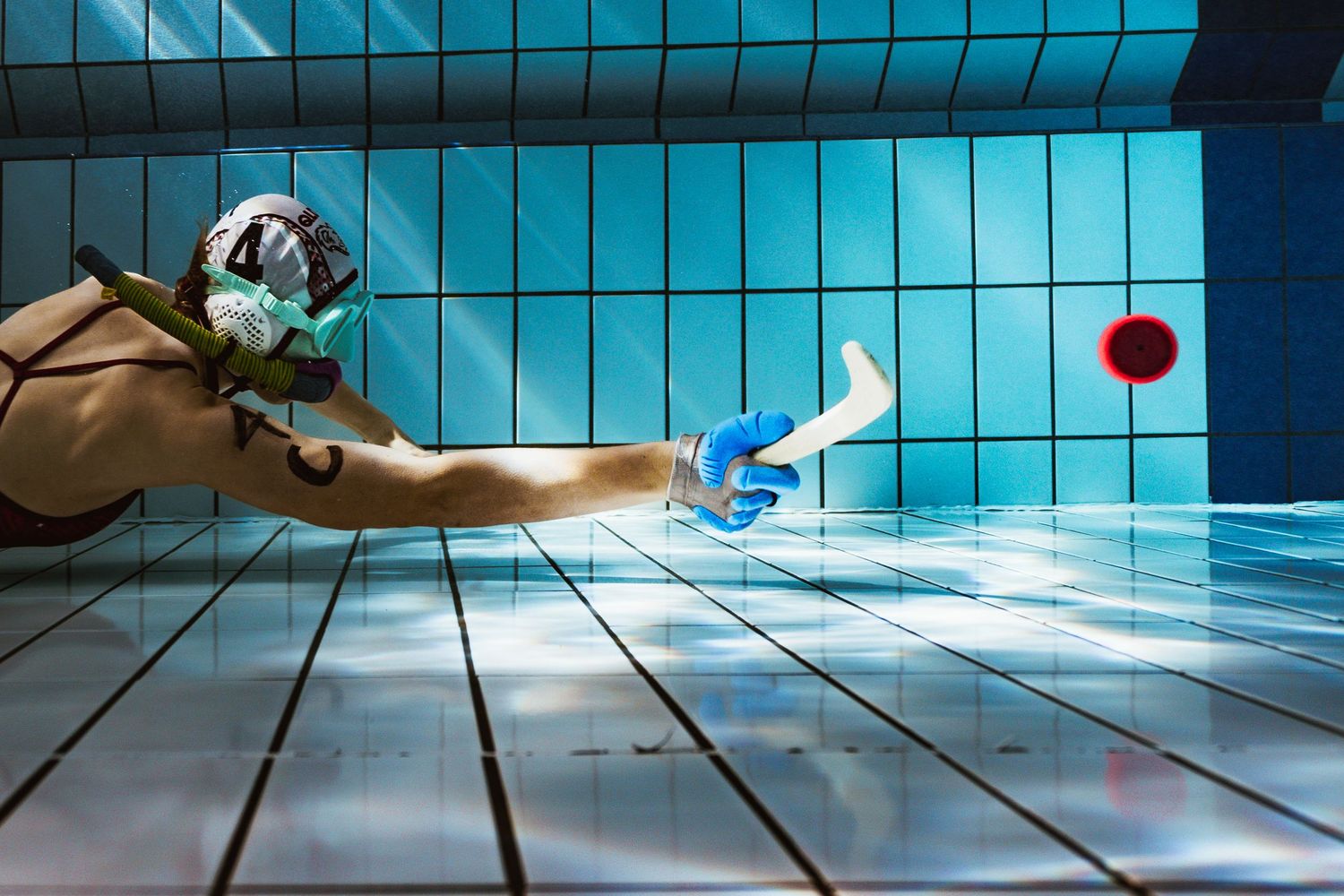 Underwater view of swimming pool tiles with blue reflections.