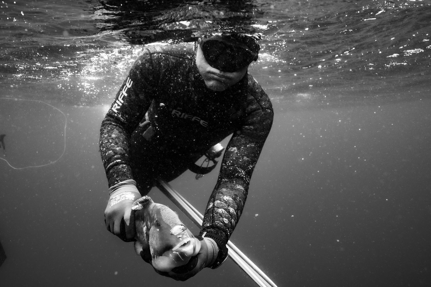 Underwater sequence of a scuba diver swimming with bubbles rising in dark blue water.