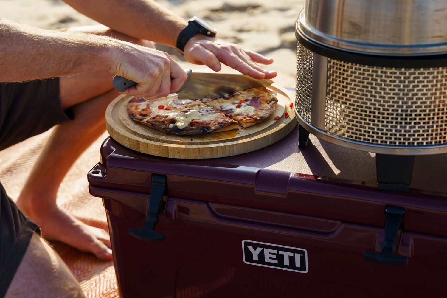Portable cooking equipment including a YETI cooler and camping stove arranged on a wooden surface.
