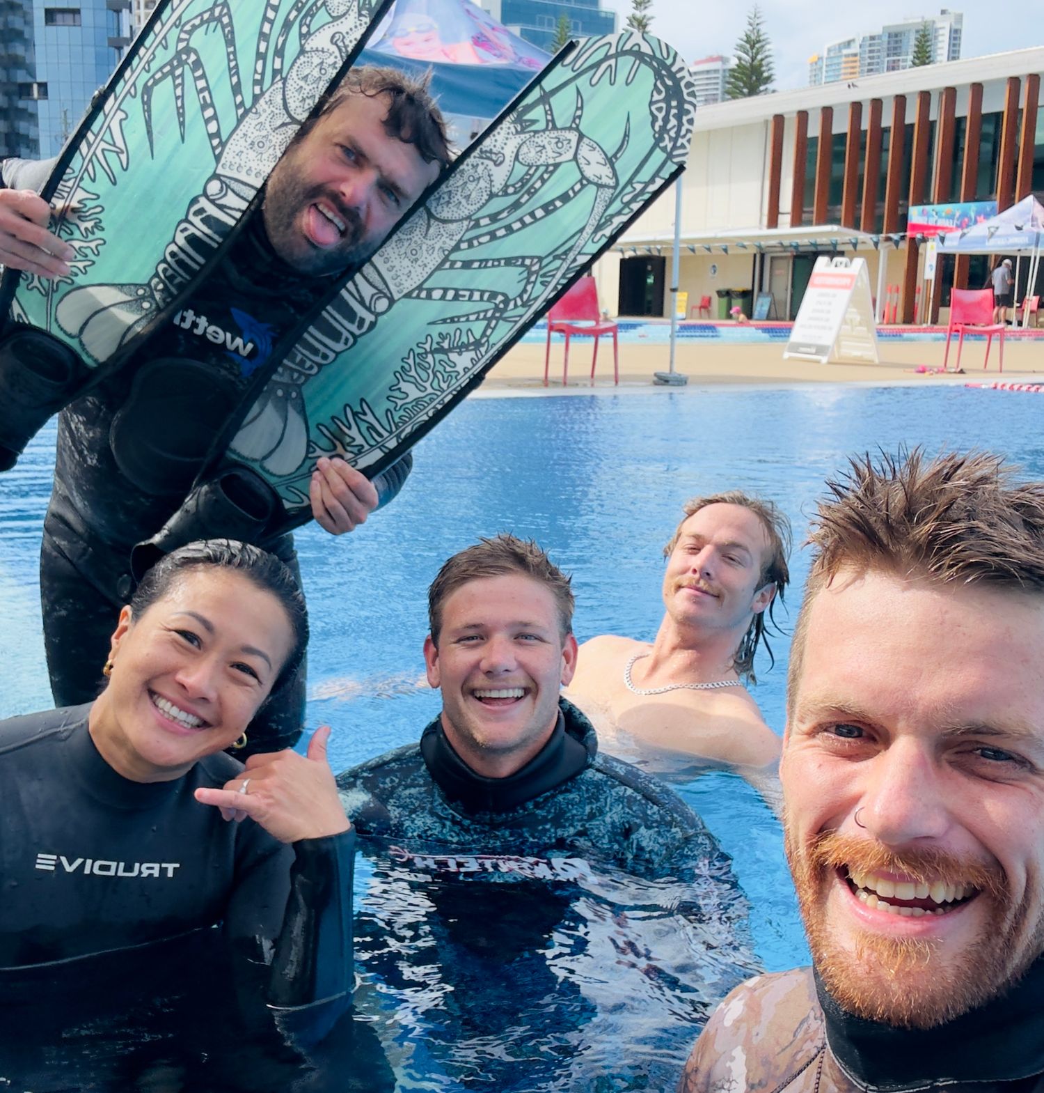 Group of friends enjoying a swim in a pool with inflatable wings.