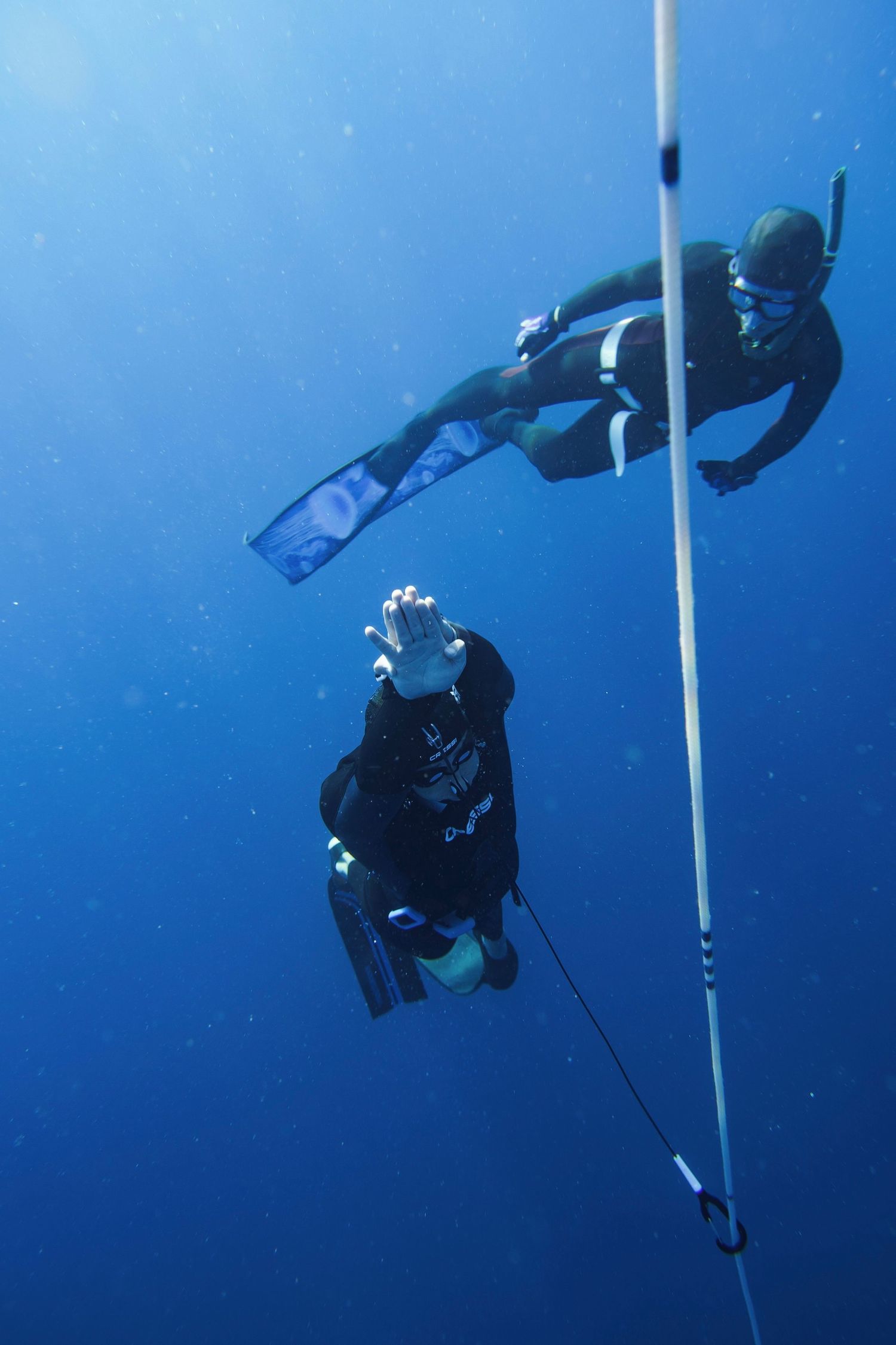 Scuba diver descending along a vertical line in deep blue ocean waters during a technical dive.