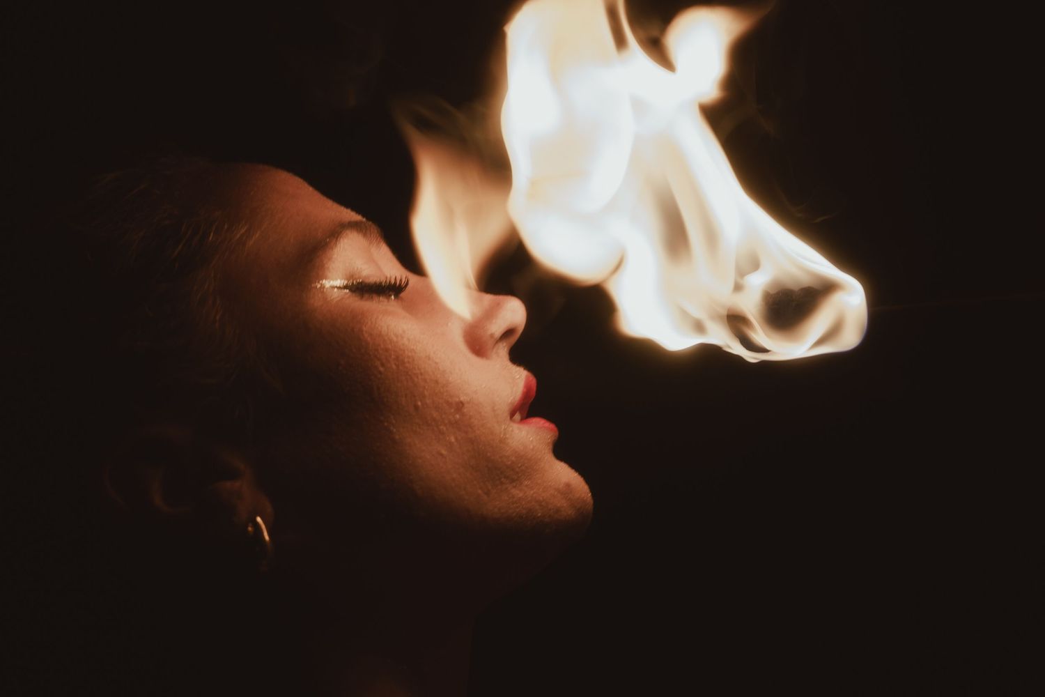 Artistic silhouette portrait with fire effects against a dark background.