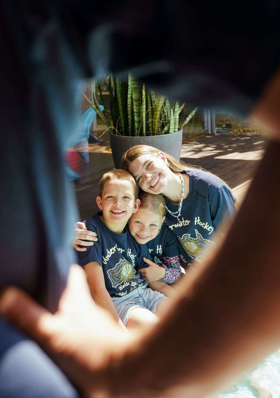 Children smiling and laughing together in a dark room with natural light streaming in.