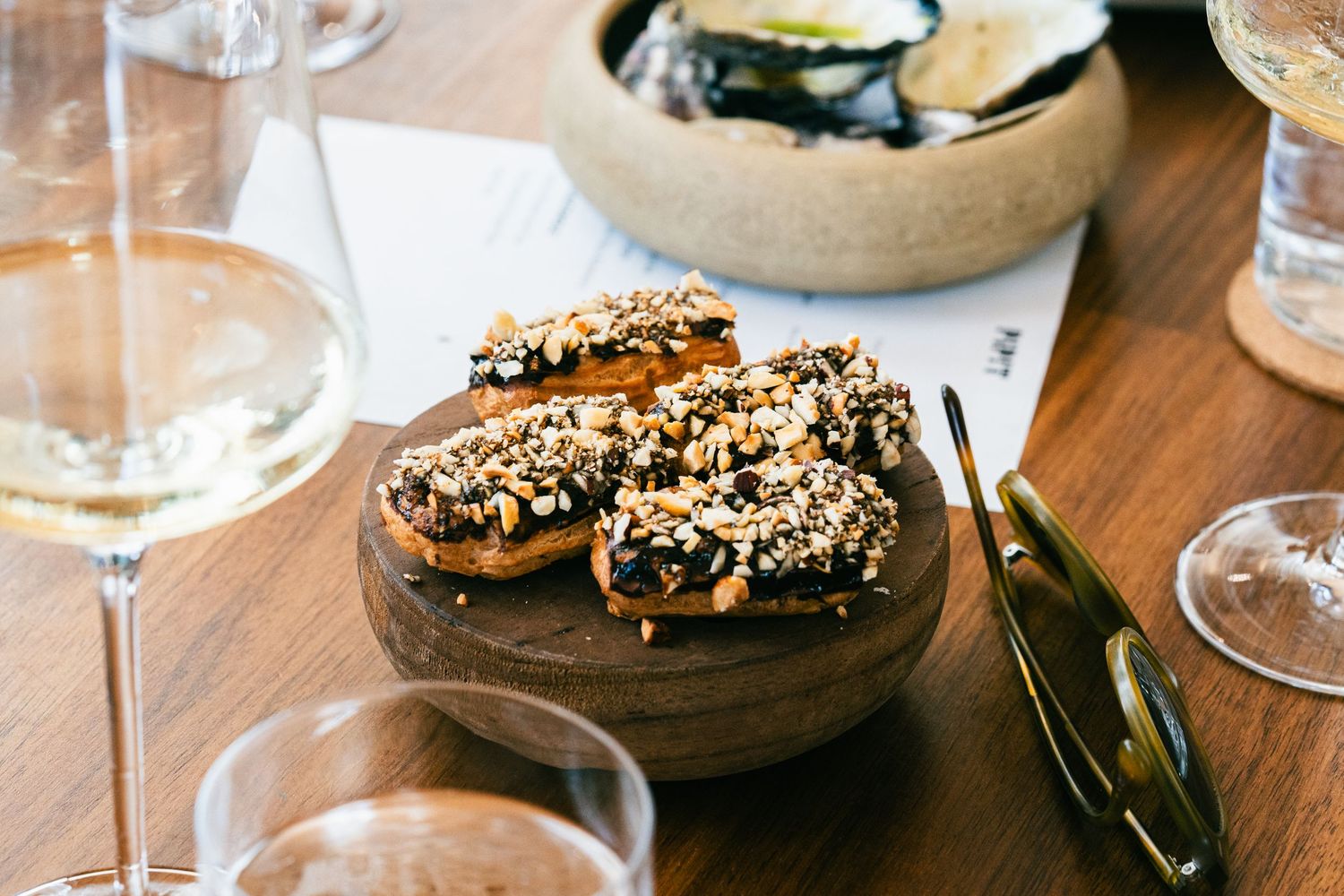 Chocolate desserts topped with nuts and caramel served on dark plates with wine glasses.