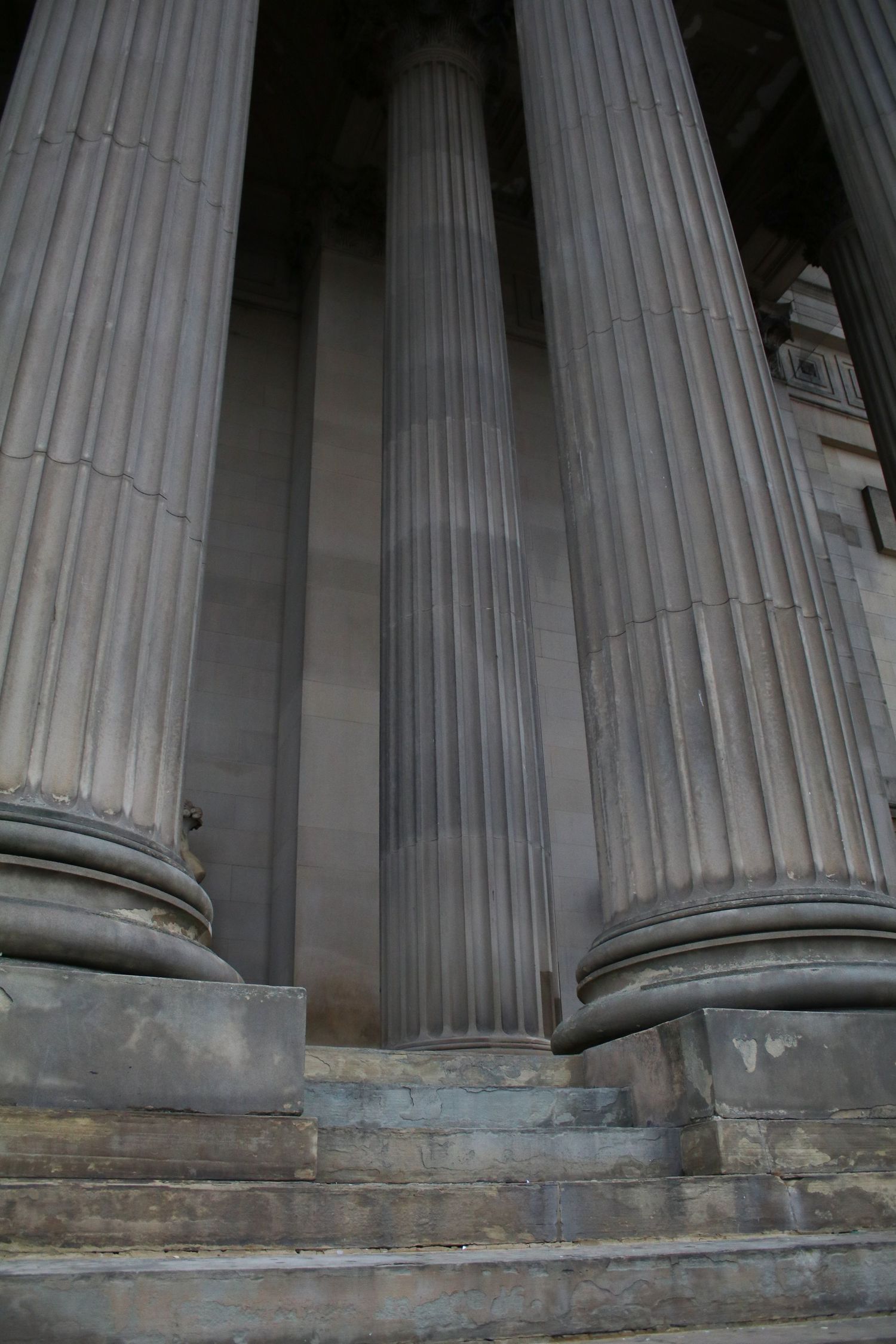 Massive fluted stone columns with stepped base at a neoclassical government building entrance.