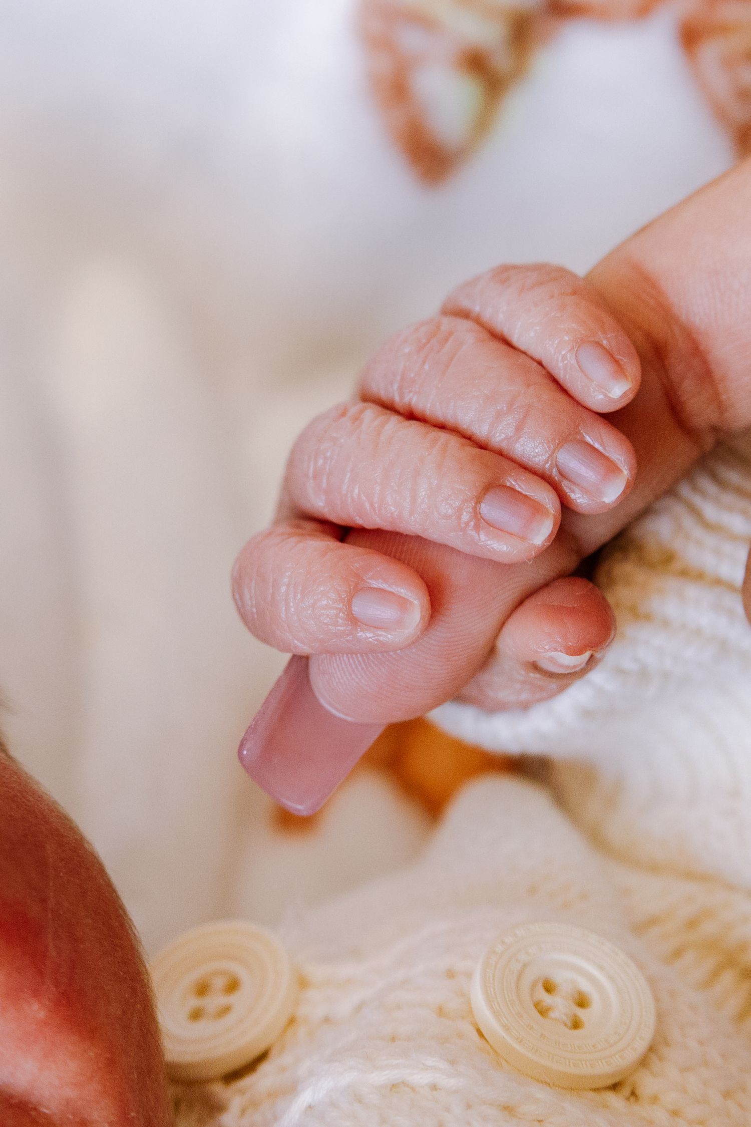 Newborn baby's tiny hand gently gripping an adult's finger in a tender moment.