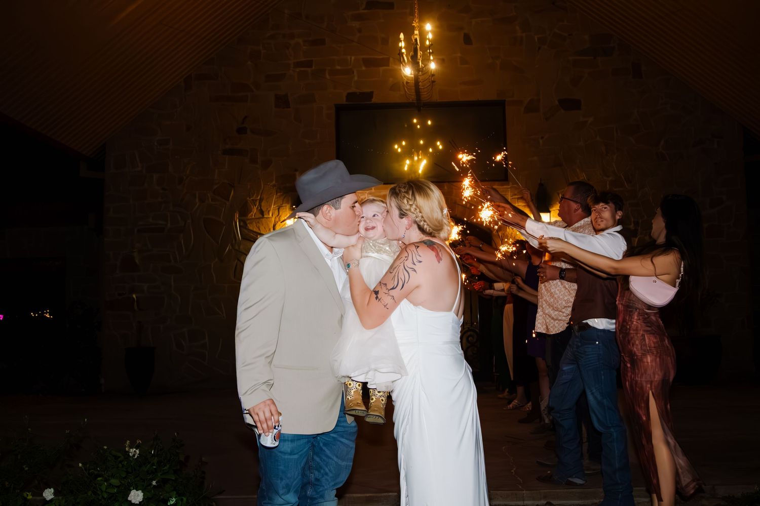 Bride and groom share a kiss during a sparkler send-off at their outdoor evening wedding reception.