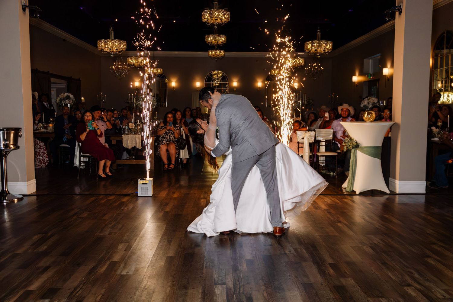 Bride and groom share first dance with sparkling fountains at elegant wedding reception venue.