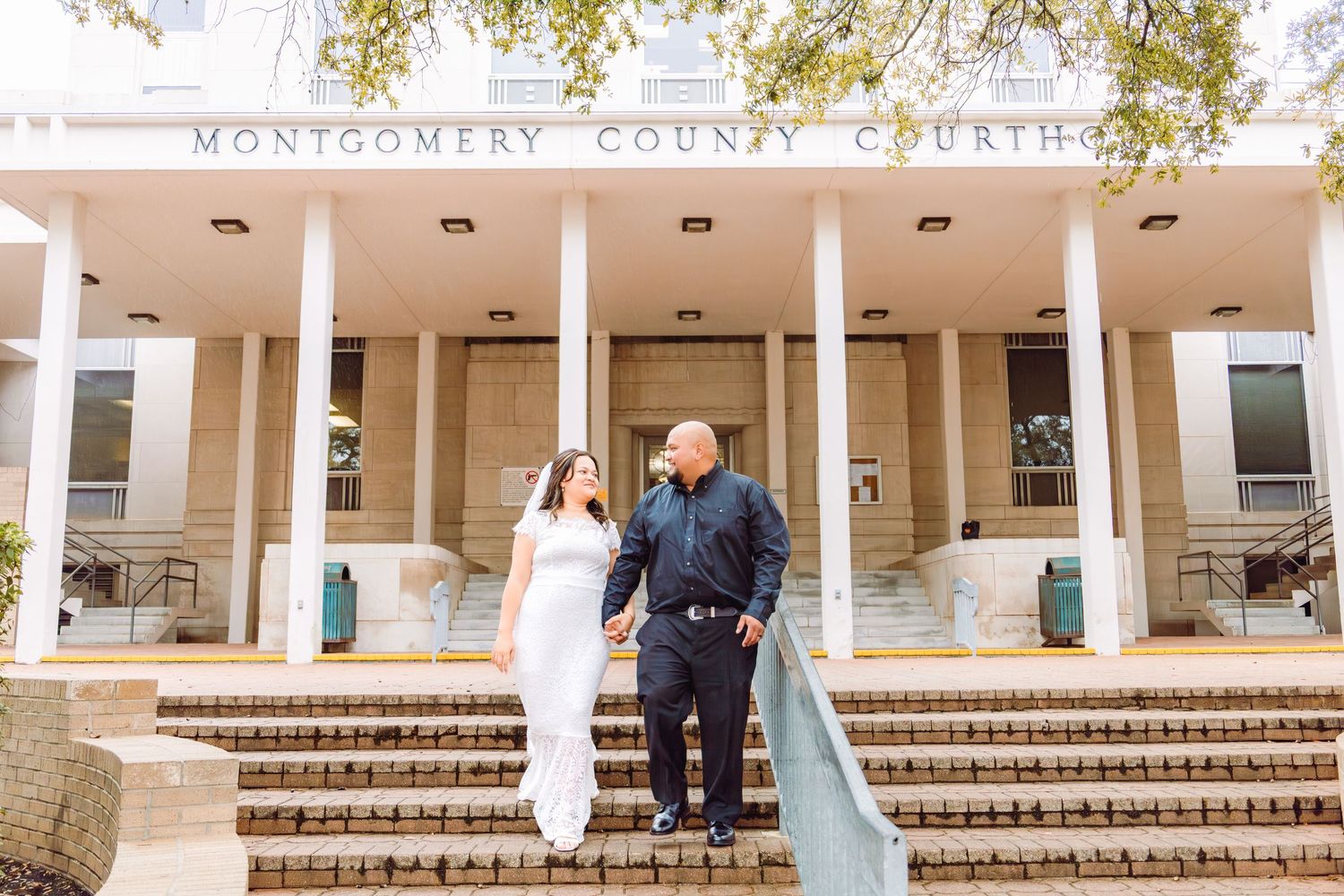 Bride and groom holding hands on steps outside Montgomery County Courthouse on their wedding day.