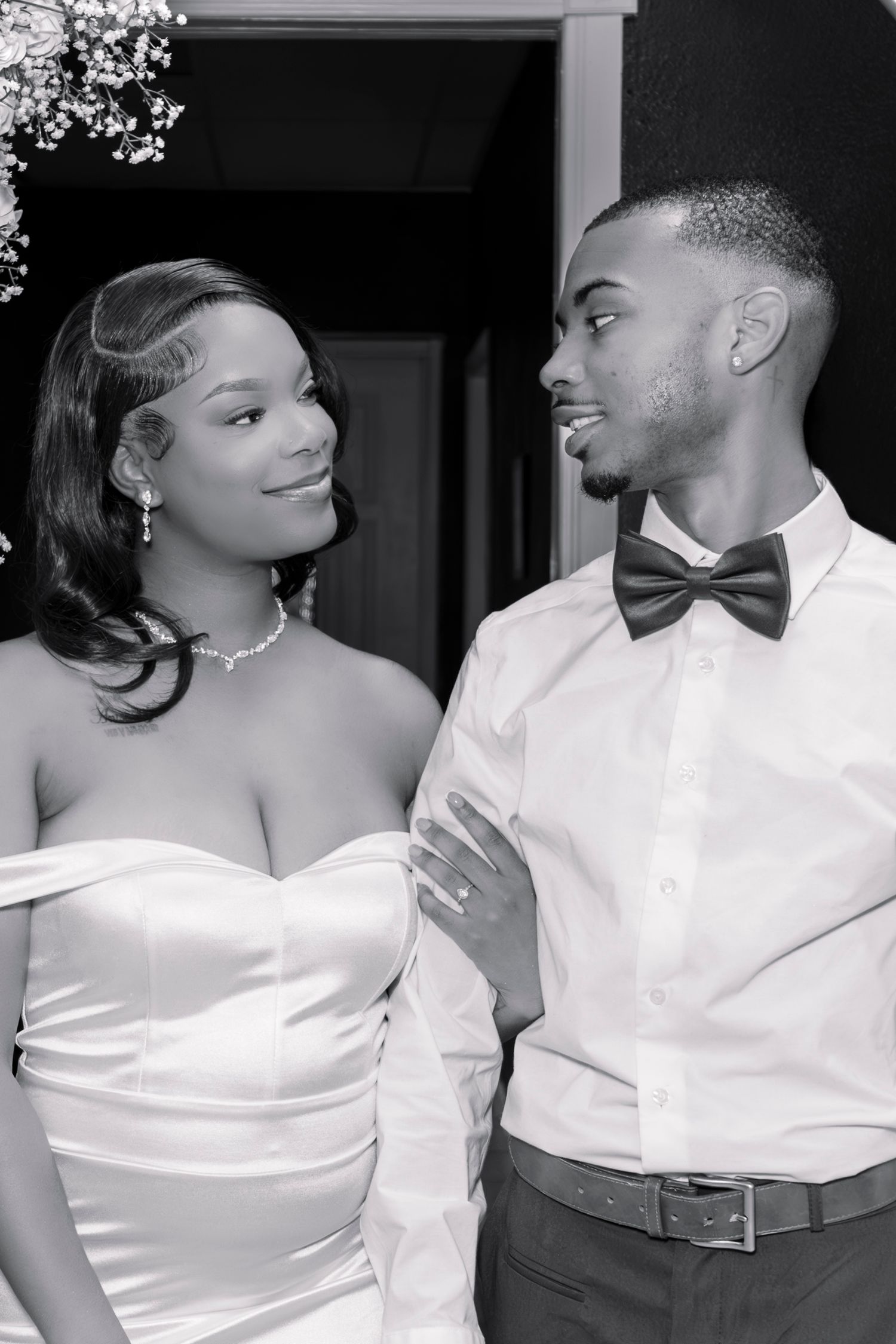 Black and white portrait of a smiling bride and groom in bow tie gazing at each other lovingly.