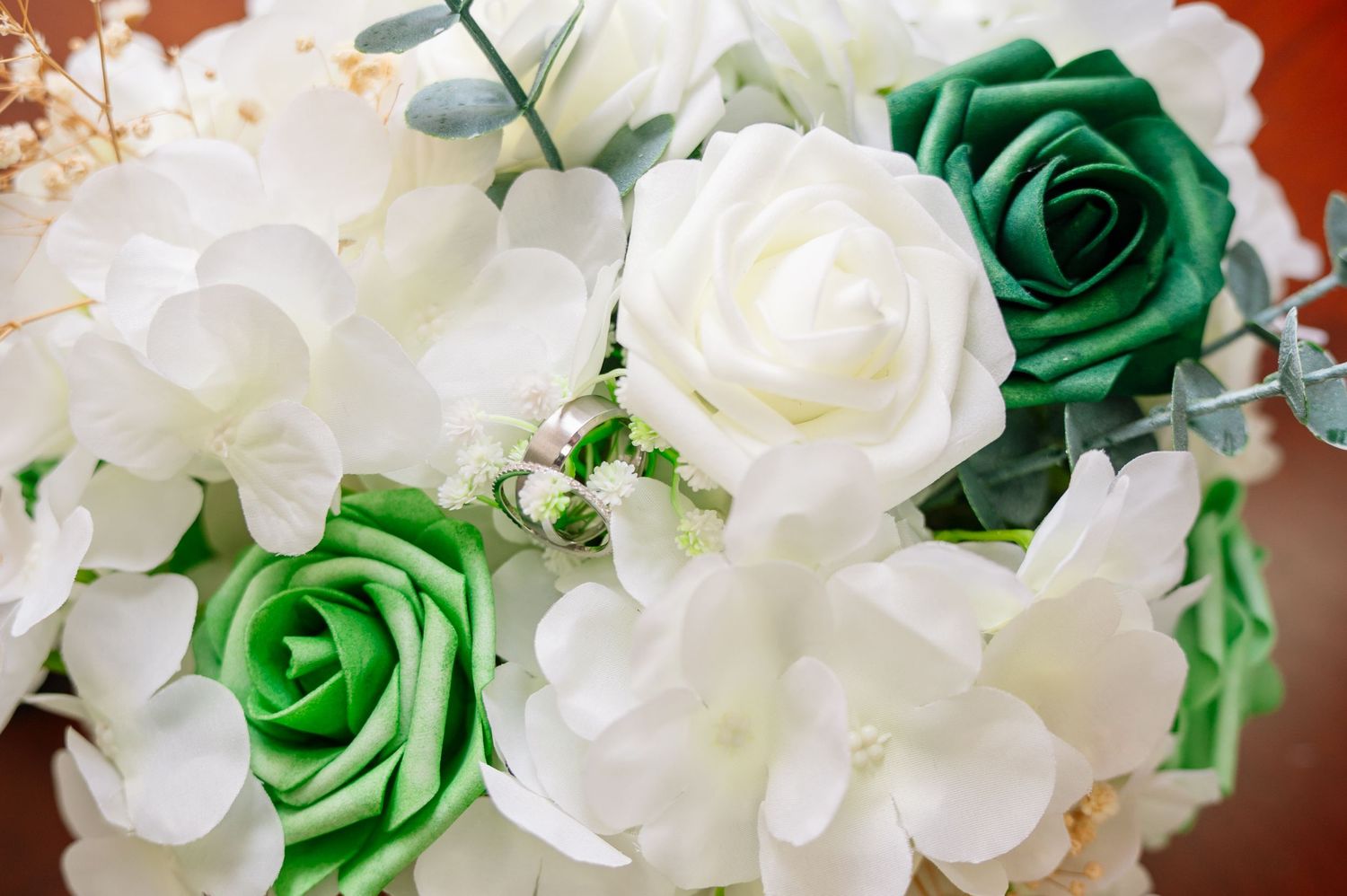 Beautiful wedding bouquet featuring green and white roses with hydrangeas and eucalyptus greenery.
