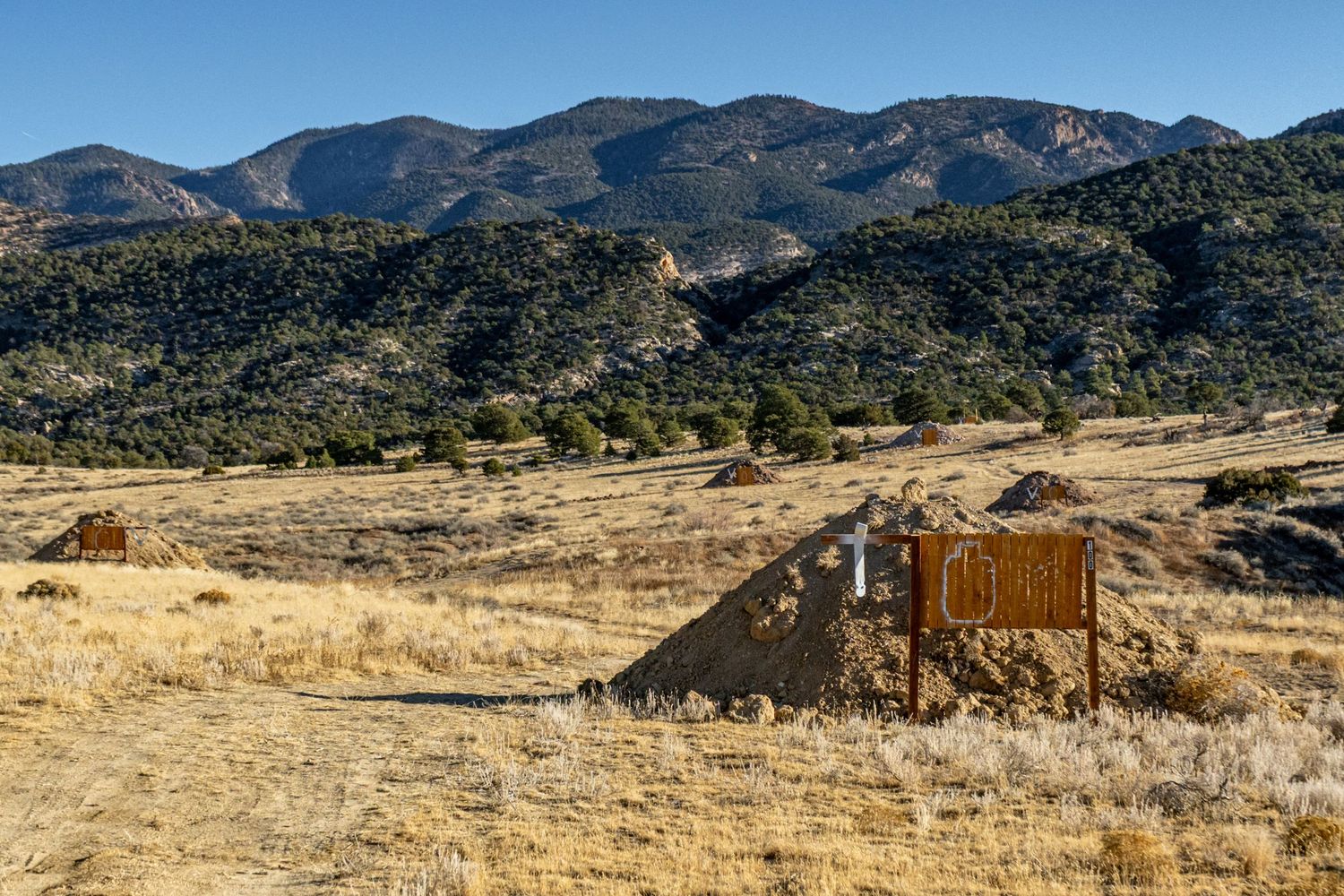Rugged mountain landscape with desert scrubland and wooden structures in the valley.