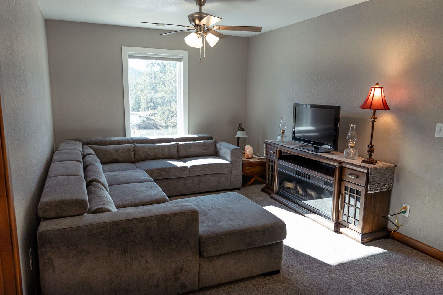 Living room with large sectional sofa, TV stand, and window providing natural lighting.