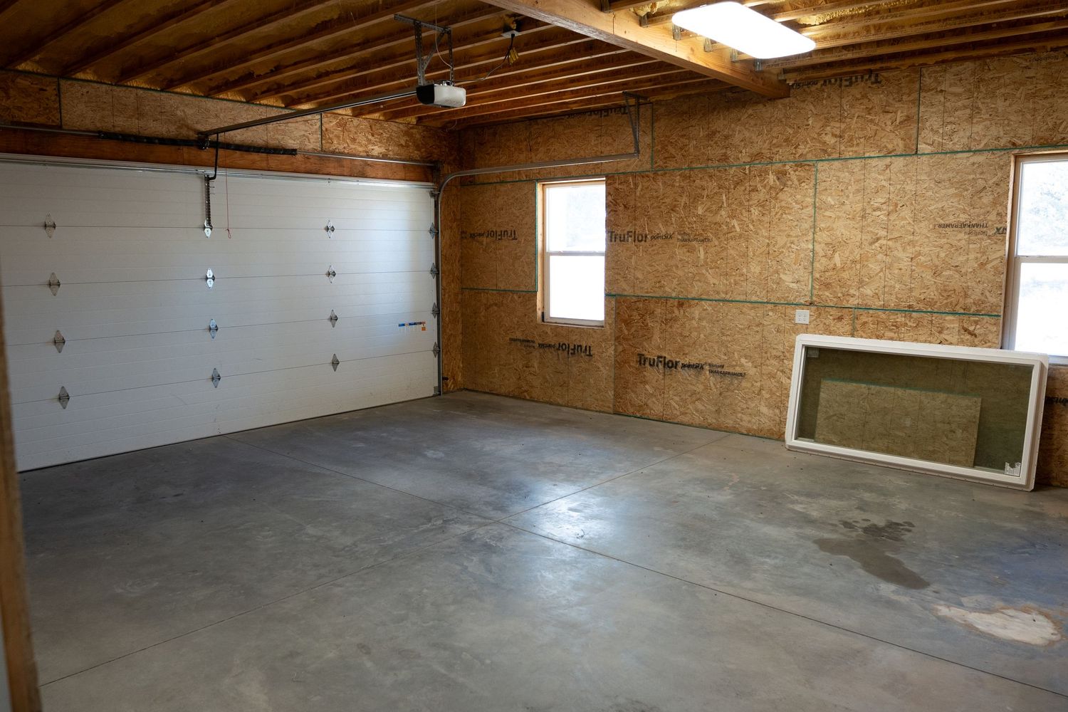 Unfinished garage interior with concrete floor and exposed wooden walls.