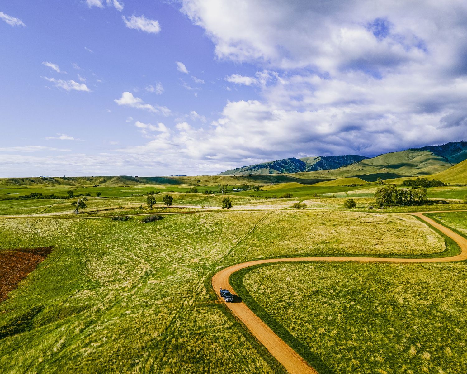 Aerial view of dirt trails winding through golden and green prairie landscape.