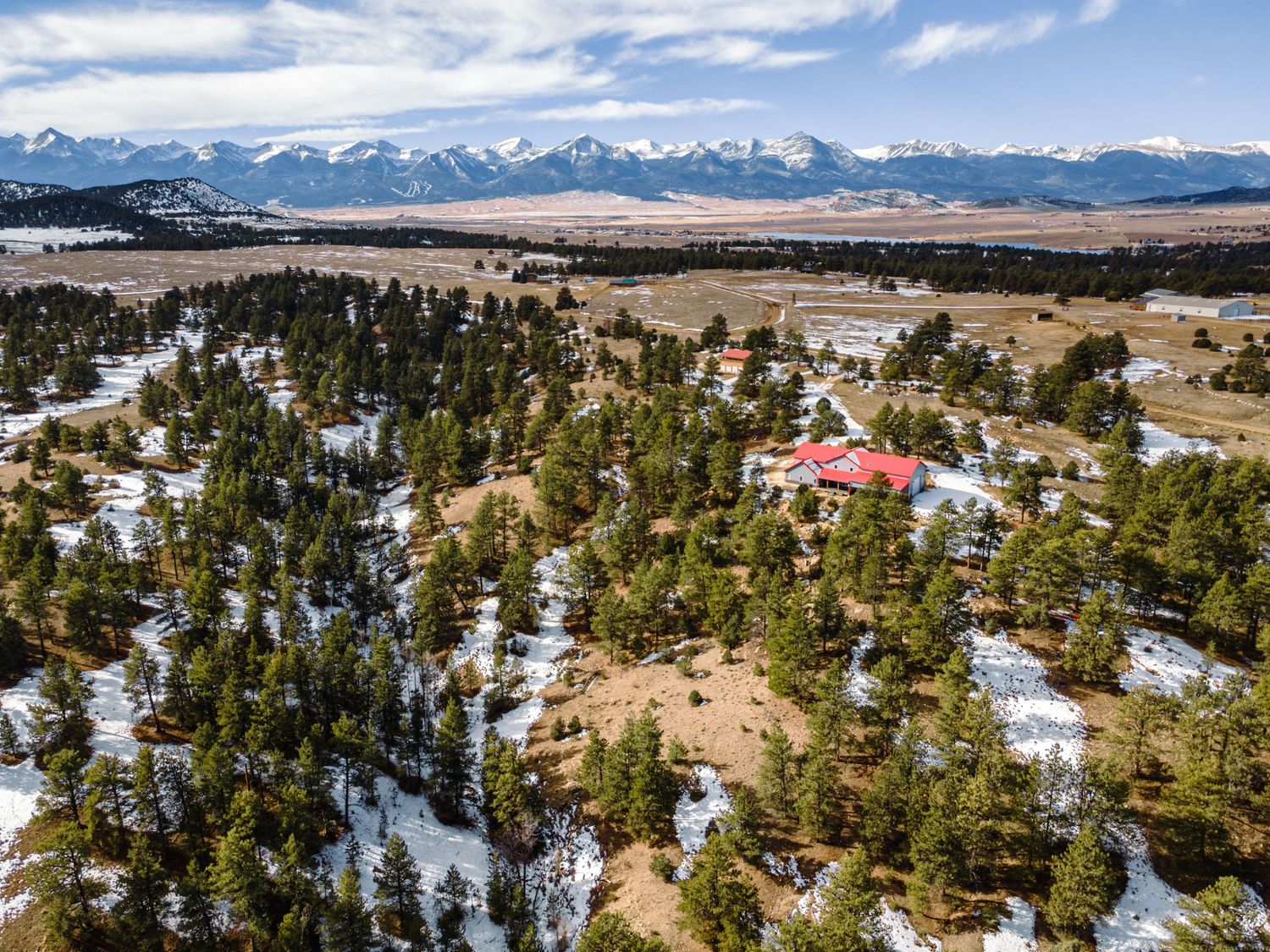 Winter landscape showing mountain ranges and forested slopes with scattered snow coverage.