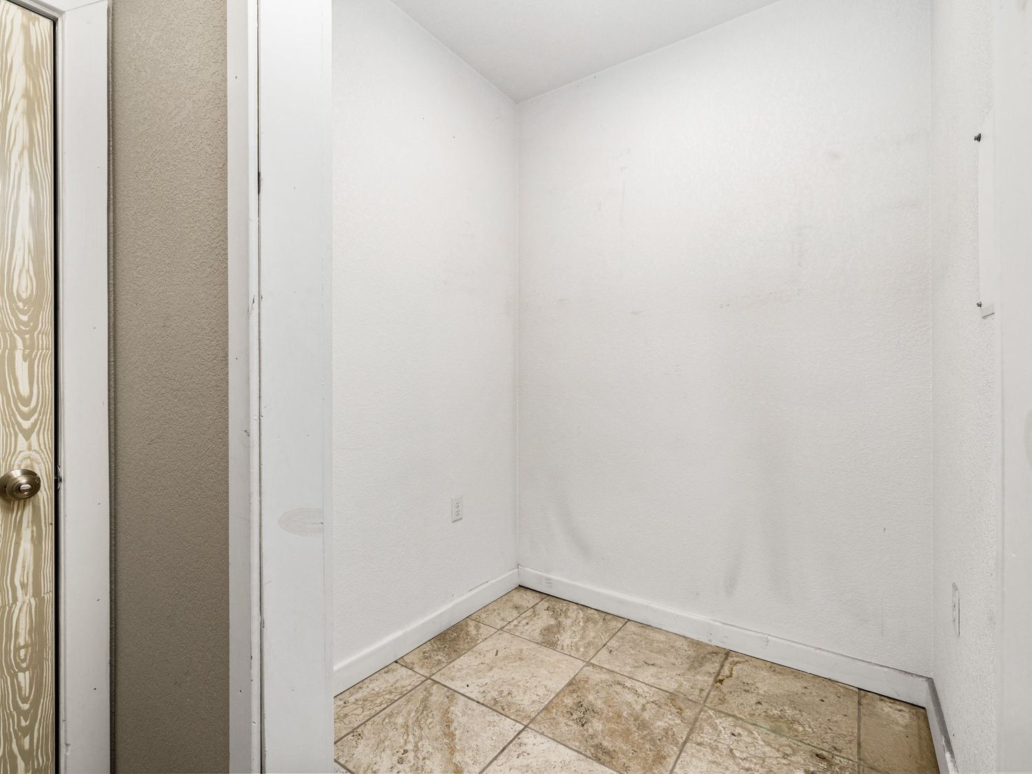 Empty laundry or utility room with white walls and beige tile flooring.