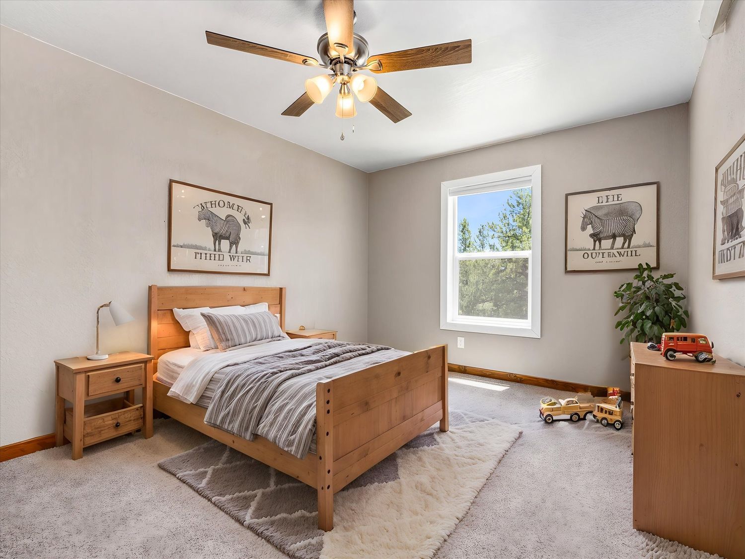 Cozy bedroom with wood bed frame, ceiling fan, carpet, and farmhouse wall art in neutral tones.