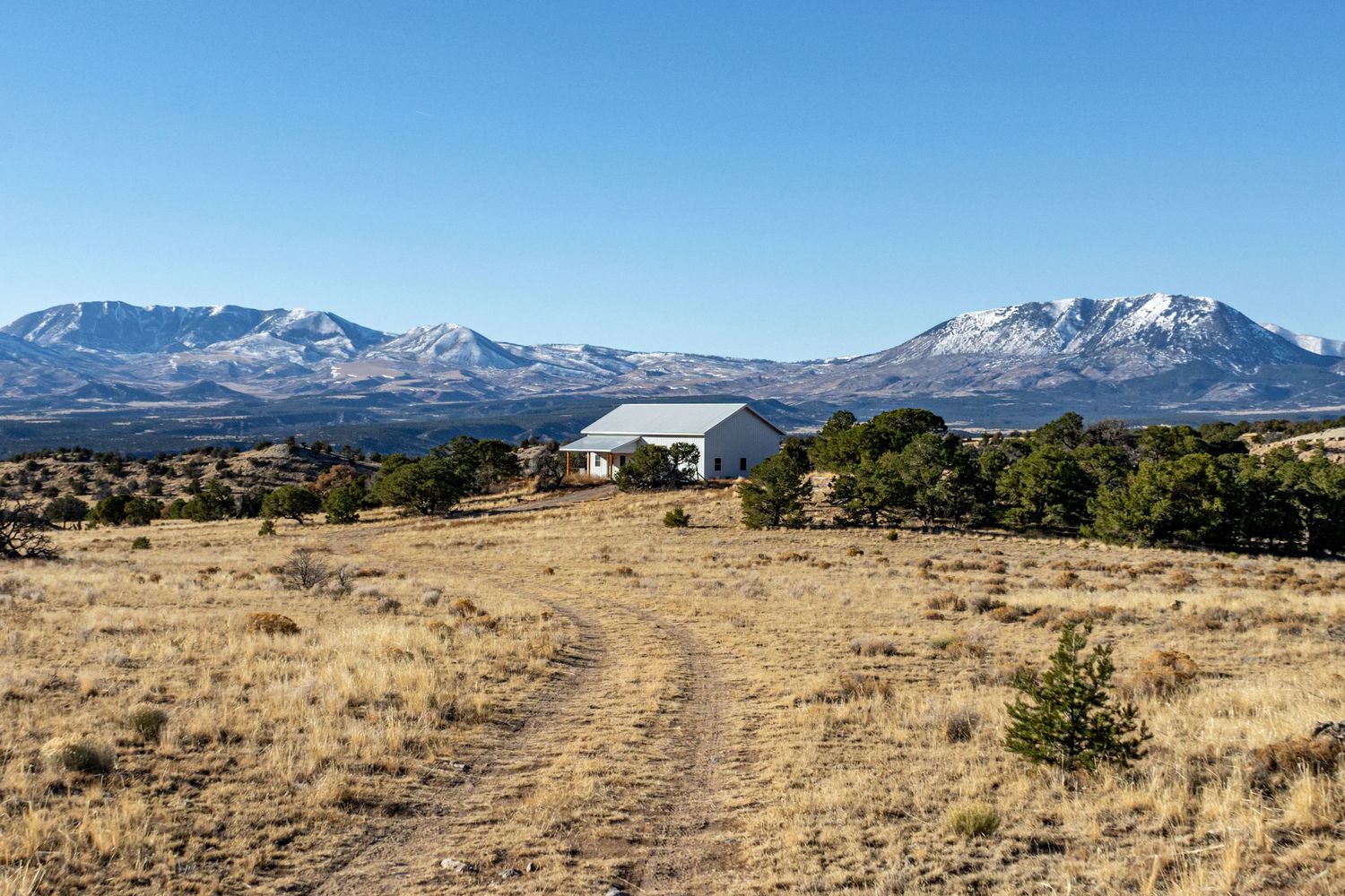 Desert plateau with snow-capped mountains and clear blue sky.